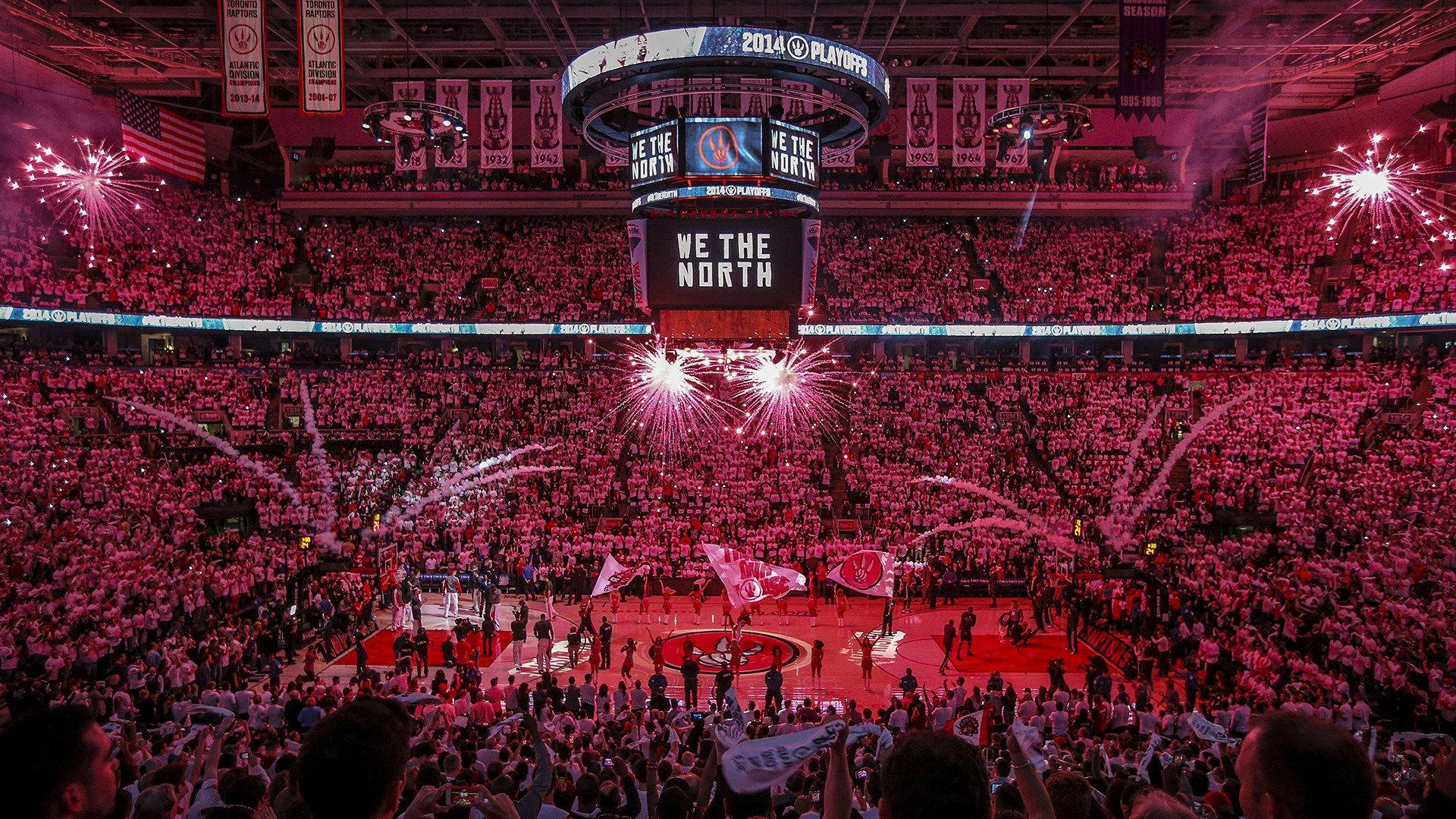 Raptors 桌布 壁紙 — 一個擠滿人的籃球場爆發粉紅色煙火，球迷在巨型記分板下高喊「we the north」。