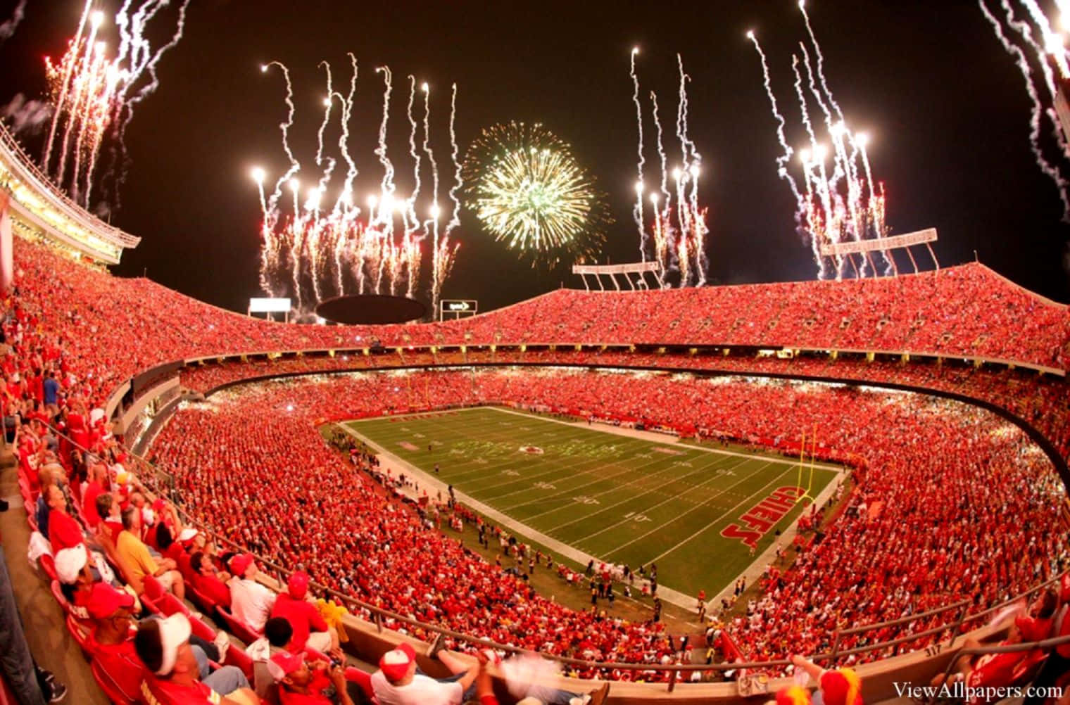 Stadium 桌布 壁紙 — 一個擠滿人的足球場在夜晚被球場上方綻放的耀眼煙火照亮。
