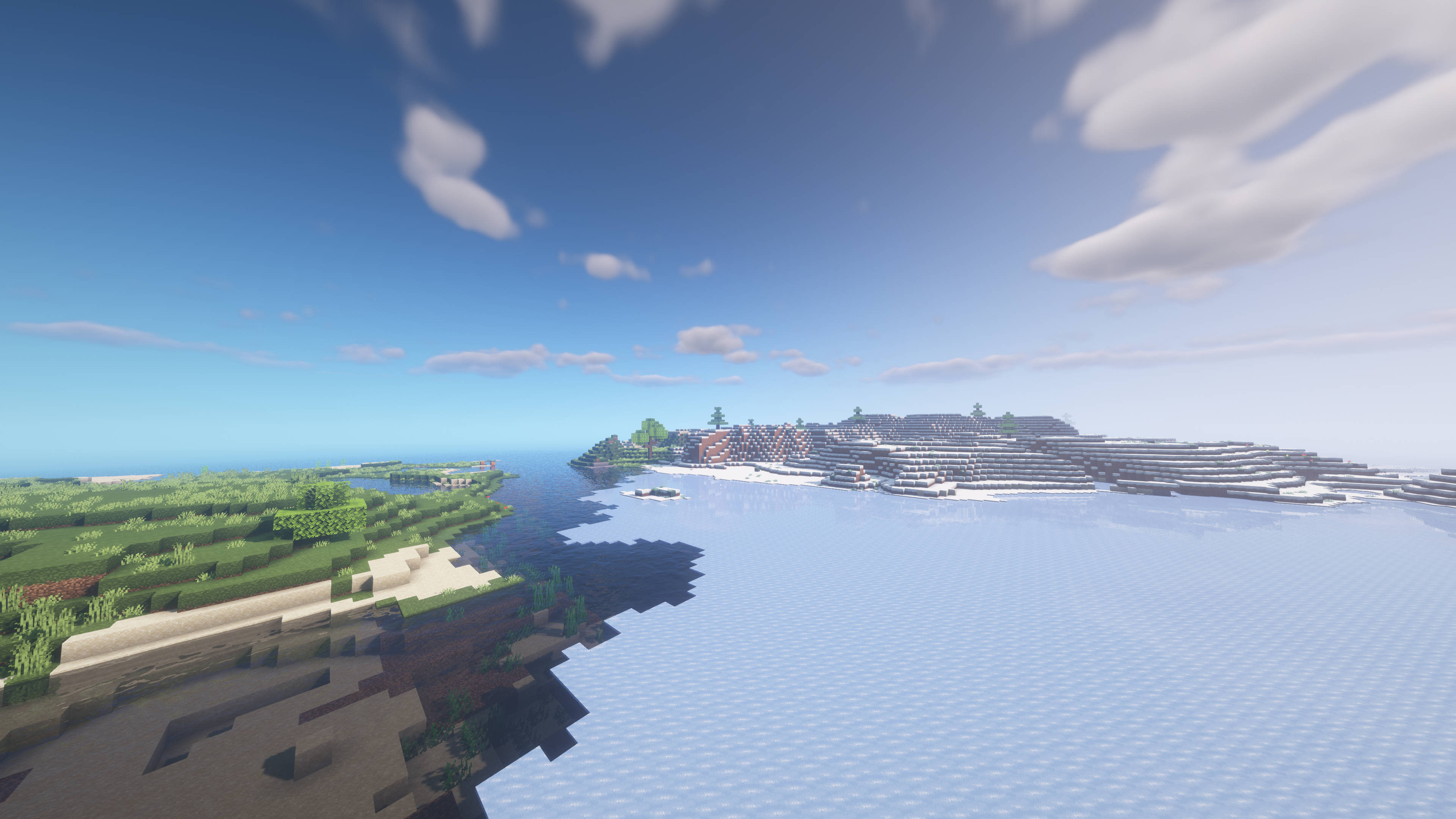 Lake 桌布 壁紙 — 一個方塊狀的Minecraft村莊坐落在白雪皚皚的山坡上，俯瞰著平靜的海洋，上方是明亮的藍天和蓬鬆的雲朵。