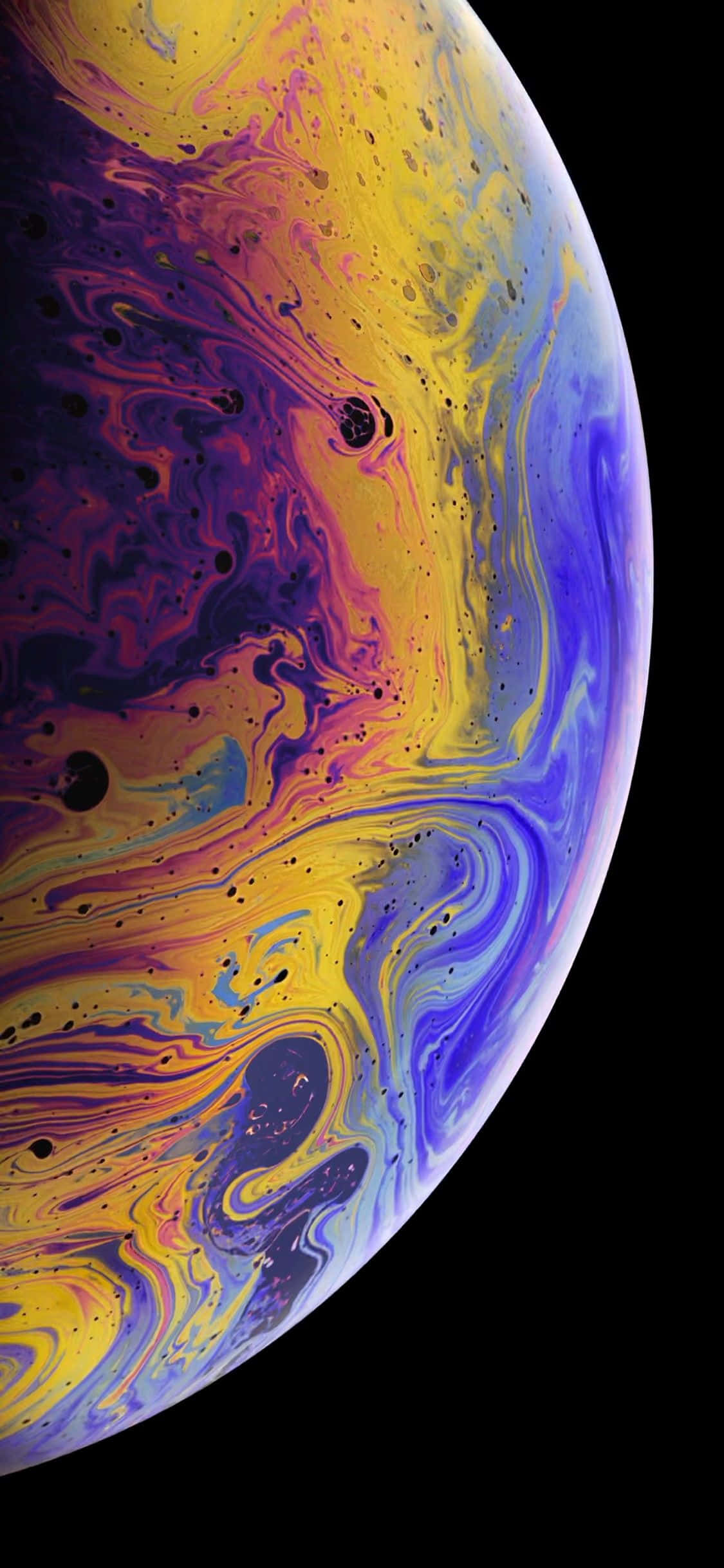 Apple iPhone Xs Max 桌布 壁紙 — 一個旋轉的宇宙球體，帶有鮮豔的黃色、紫色和藍色色調，背景是黑色虛空。