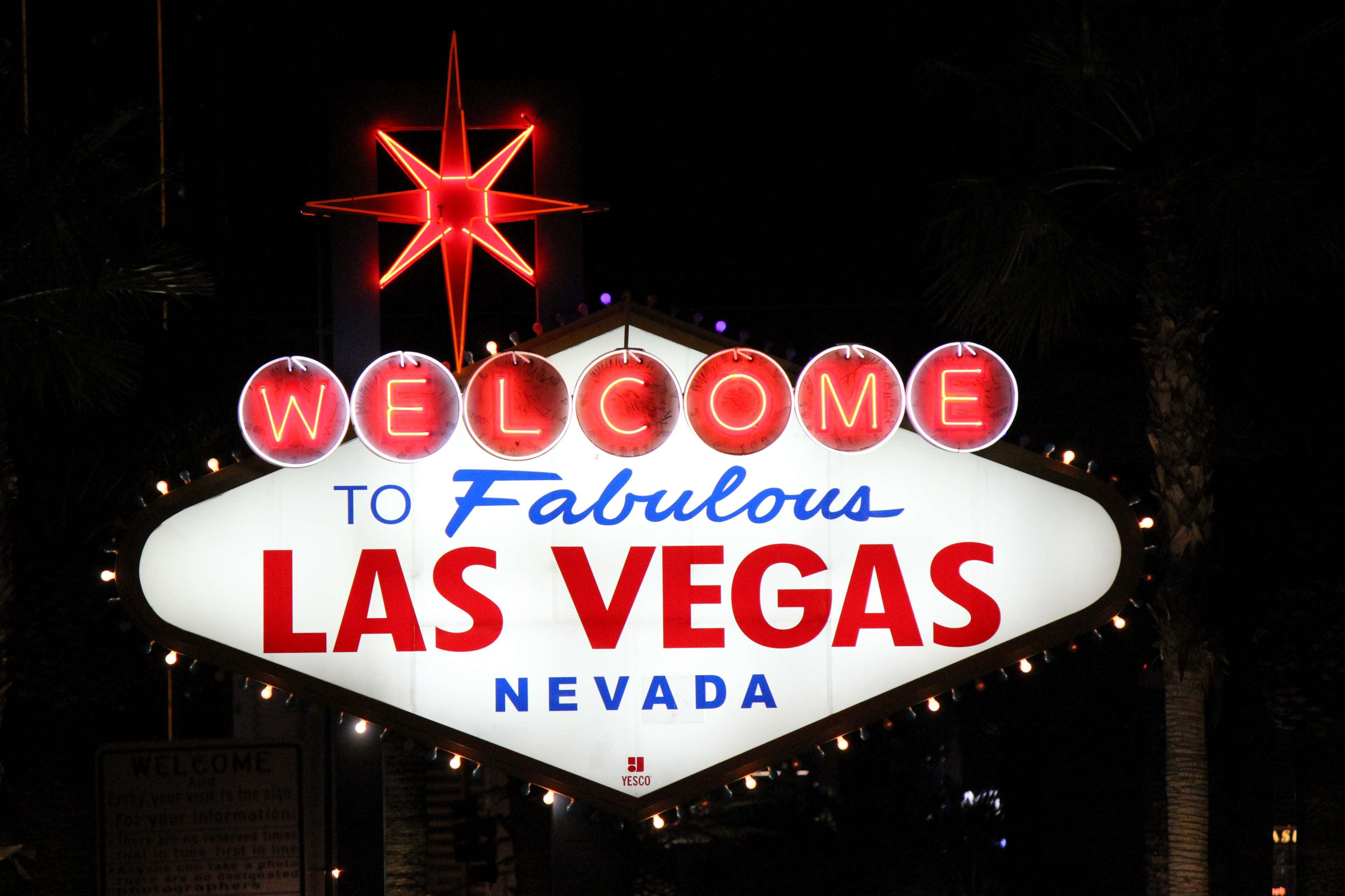 4K Las Vegas 桌布 壁紙 — 一個明亮照明的霓虹招牌，上面寫著「Welcome to Fabulous Las Vegas Nevada」，在漆黑的夜空下閃耀，背後襯托著棕櫚樹的剪影。