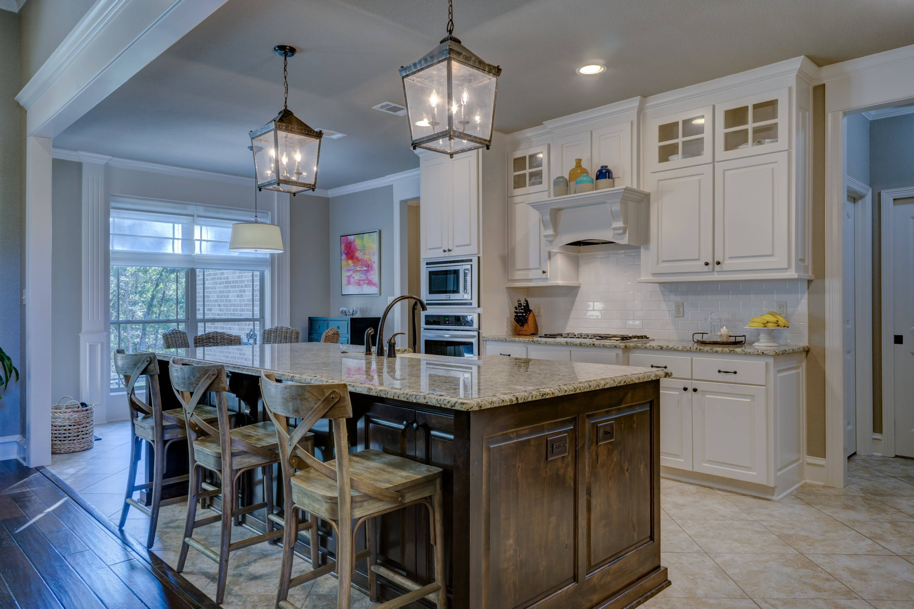 Kitchen Design 桌布 壁紙 — 一個明亮的現代廚房，配有白色櫥櫃、深色木島和掛燈下的鄉村風格吧檯凳。