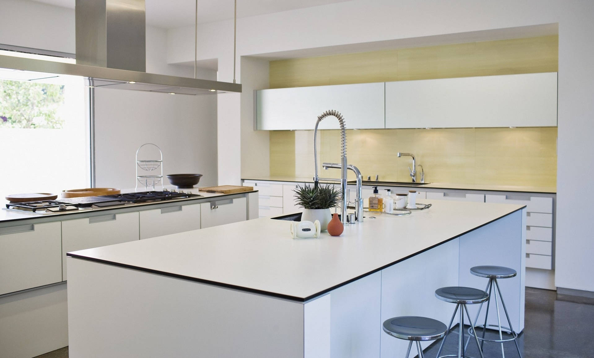 Interior Design 桌布 壁紙 — 一個明亮的現代廚房，配有白色櫥櫃、中央島檯和不鏽鋼電器，在自然光下。