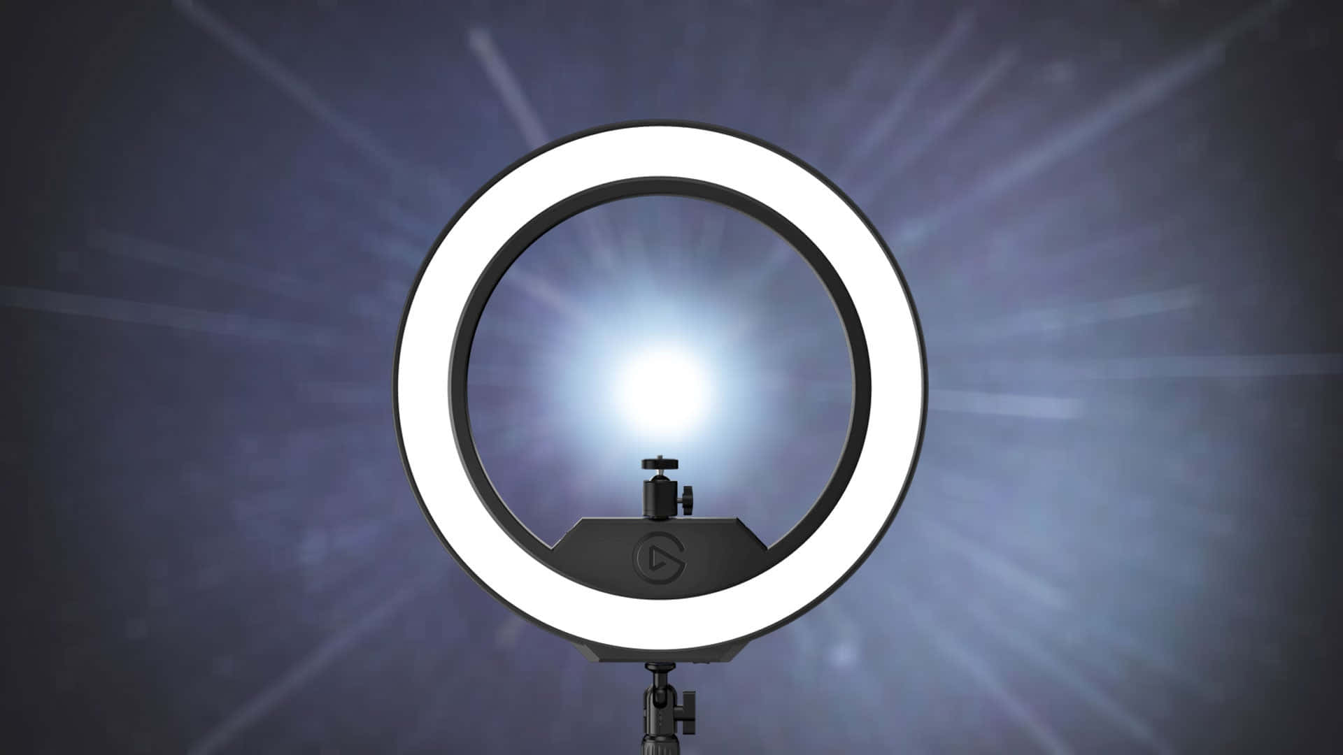 Ring Light 桌布 壁紙 — 一個明亮的白色環形燈安裝在支架上，在深藍色漸變背景上發出耀眼的光束。