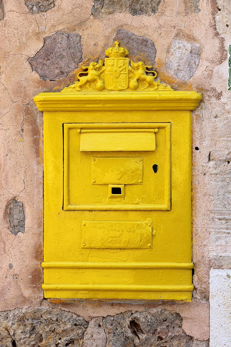 mail 桌布 壁紙 — 一個明亮的黃色復古郵箱，帶有皇家徽章和獅子圖案，安裝在風化的石牆上。
