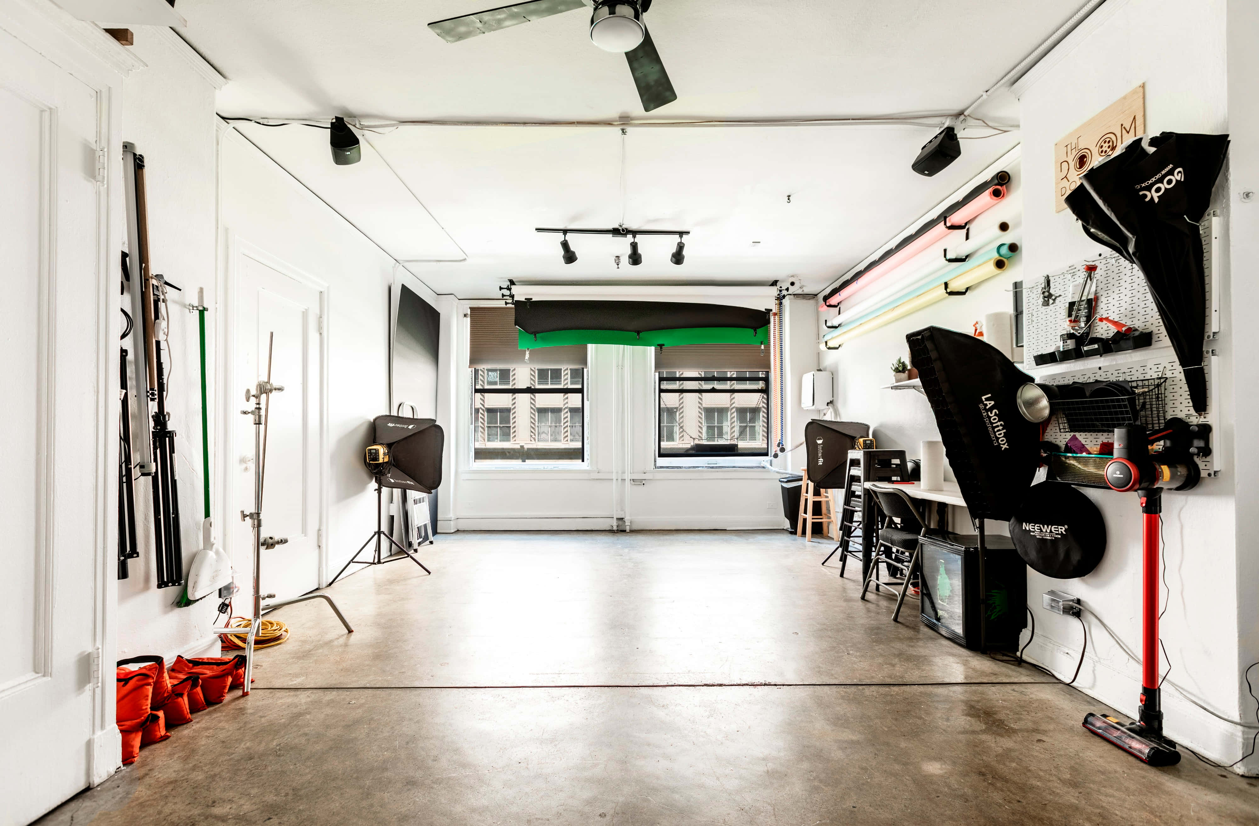 Photo Studio 桌布 壁紙 — 一個明亮簡約的攝影工作室，混凝土地板和牆壁上排列著照明設備和器材。