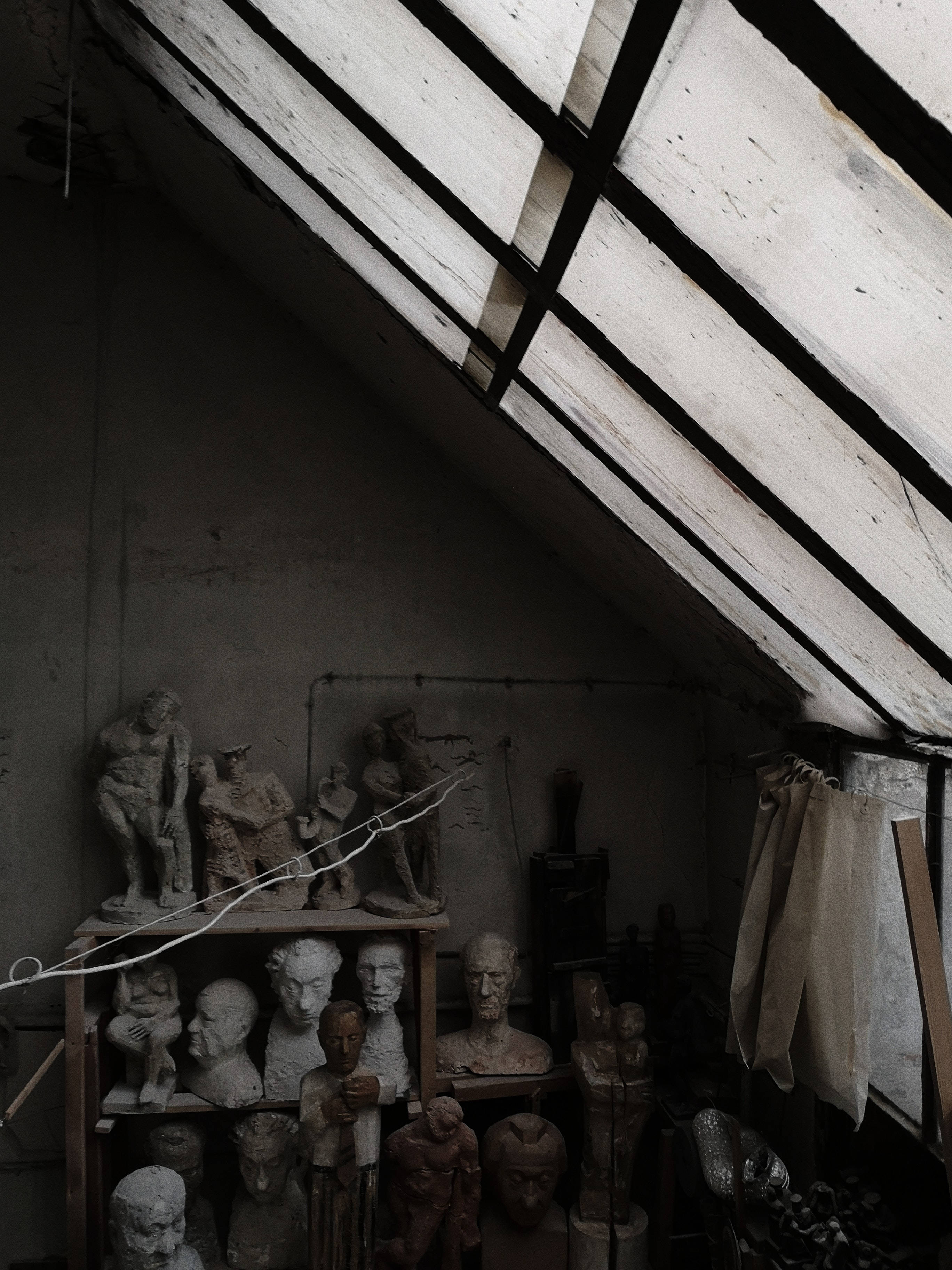 Sculpture 桌布 壁紙 — 一個昏暗的閣樓，充滿灰塵的石膏雕塑，下方是傾斜的木屋頂，帶有裸露的橫樑。
