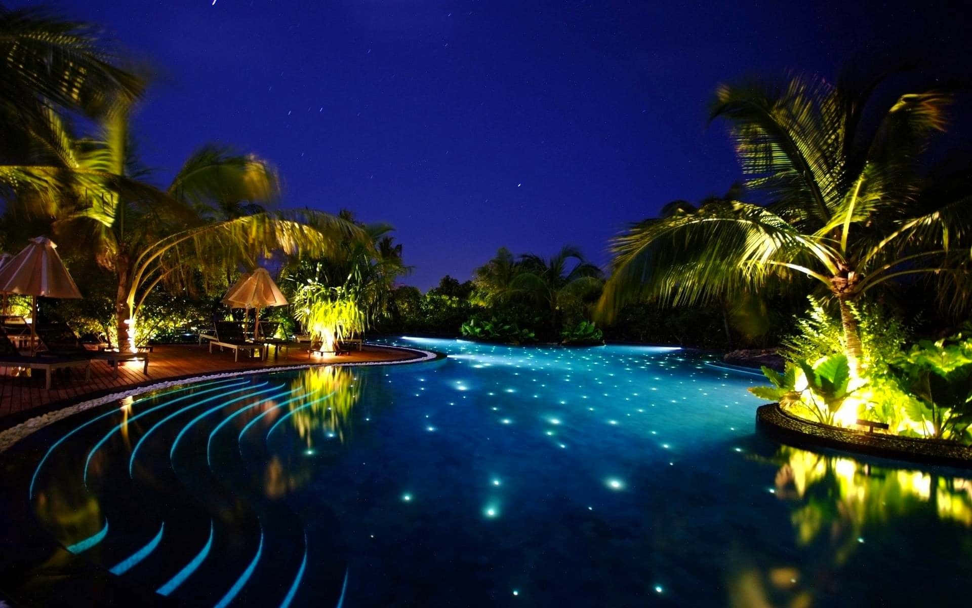 pool 桌布 壁紙 — 一個星光燦爛的夜晚泳池，散發著藍色水下燈光，周圍環繞著棕櫚樹和溫暖的燈籠。