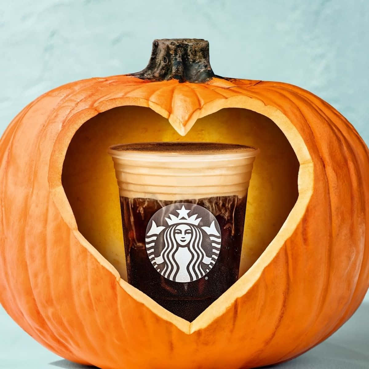 Pumpkin 桌布 壁紙 — 一個星巴克冰咖啡杯放在雕刻成心形的南瓜內，搭配溫暖燈光。