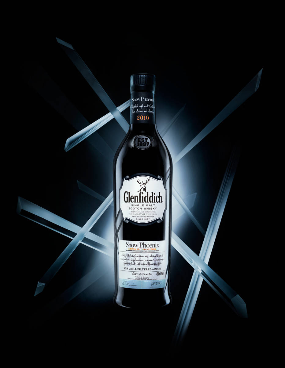 alcohol 桌布 壁紙 — 一個時尚的 Glenfiddich Snow Phoenix 威士忌酒瓶在黑暗背景下發光，帶有銳利的藍色幾何光線。