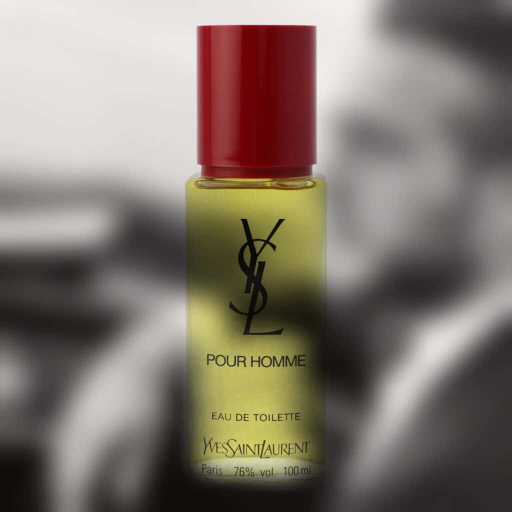 YSL 桌布 壁紙 — 一個時尚的 Yves Saint Laurent Pour Homme 香水瓶，帶有紅色瓶蓋和琥珀色液體，在模糊的黑白背景下清晰對焦。