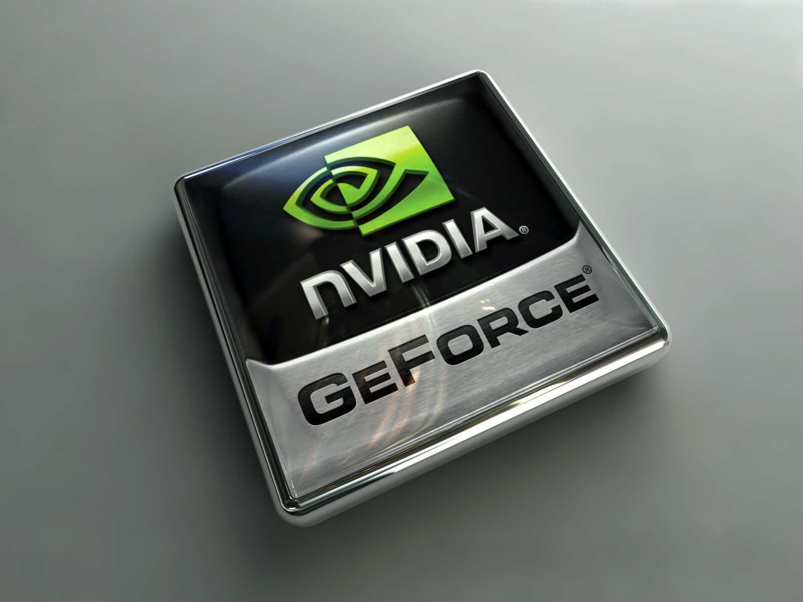 nvidia 桌布 壁紙 — 一個時尚的3D渲染Nvidia GeForce標誌晶片，帶有綠色眼睛標誌和銀色金屬質感，置於灰色表面上。