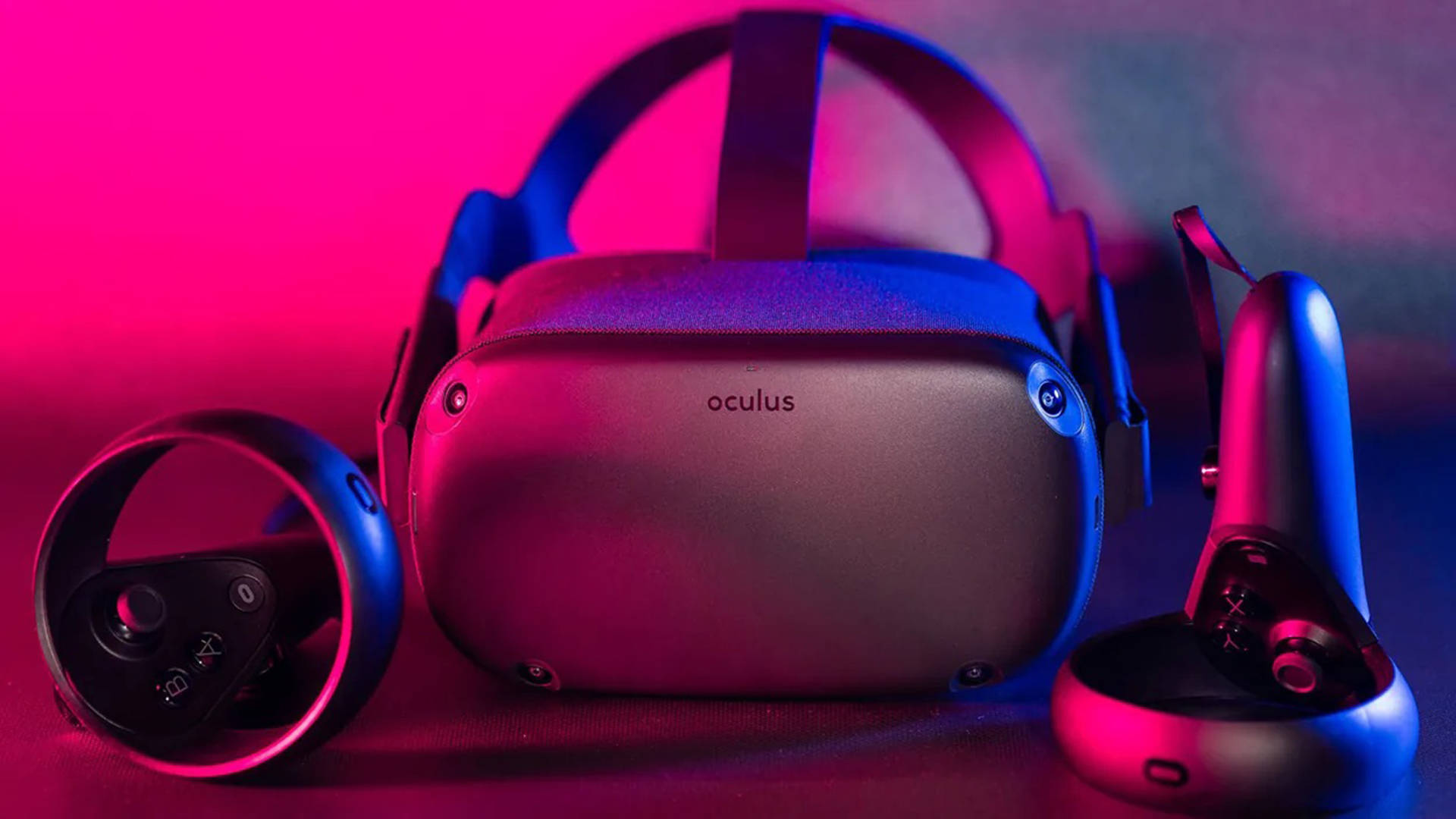 Quest 桌布 壁紙 — 一個時尚的Oculus VR頭戴式裝置和控制器，在黑暗的表面上沐浴在充滿活力的粉紅色和藍色霓虹燈中。