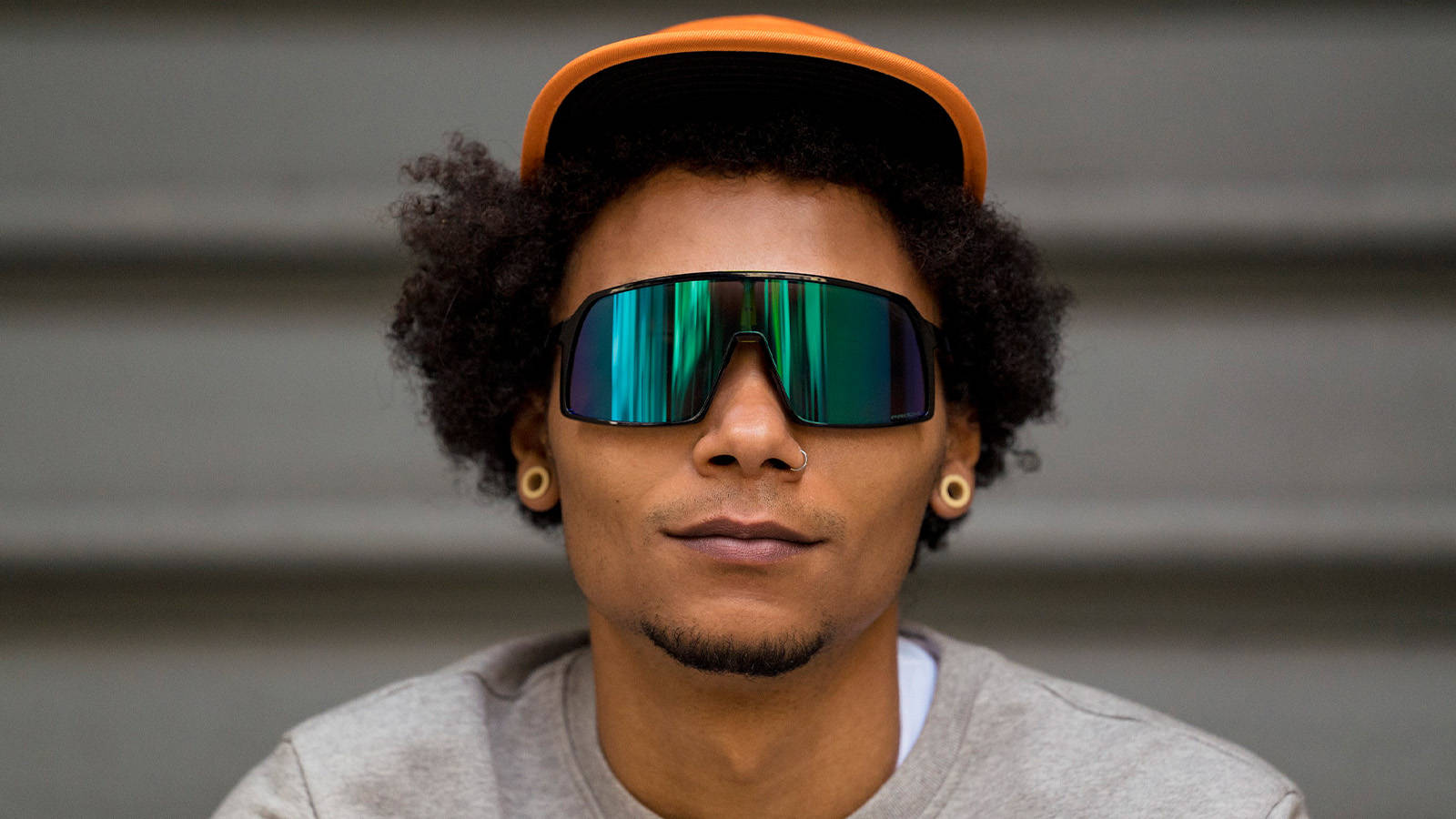 Sunglasses 桌布 壁紙 — 一個時尚的人，有捲髮，戴著搶眼的橙色帽子和反光綠色太陽眼鏡，背景是灰色的瓦楞紙。