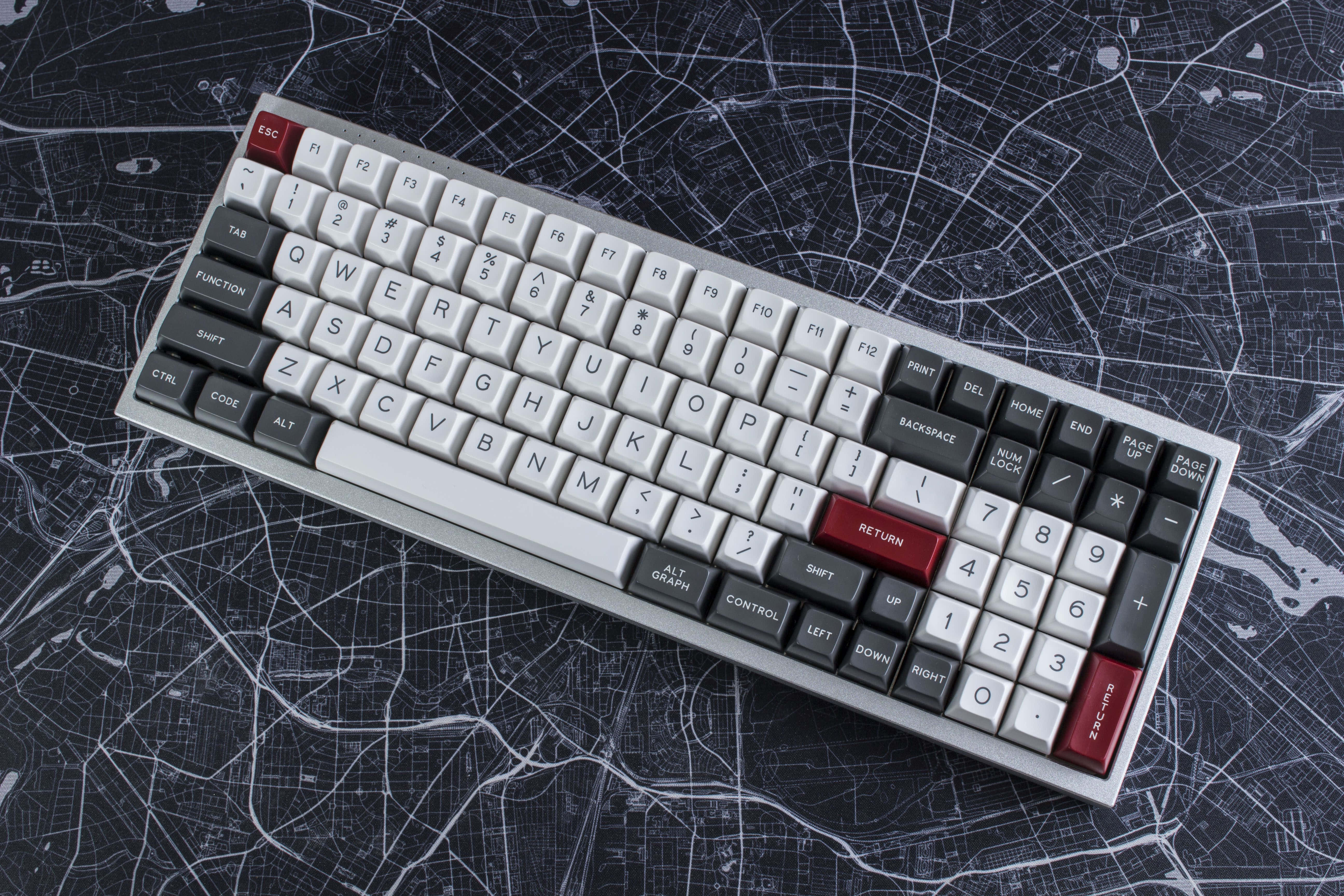 Gaming Keyboards 桌布 壁紙 — 一個時尚的機械鍵盤，帶有白色和紅色按鍵，放置在顯示城市街道的深色地圖背景上。