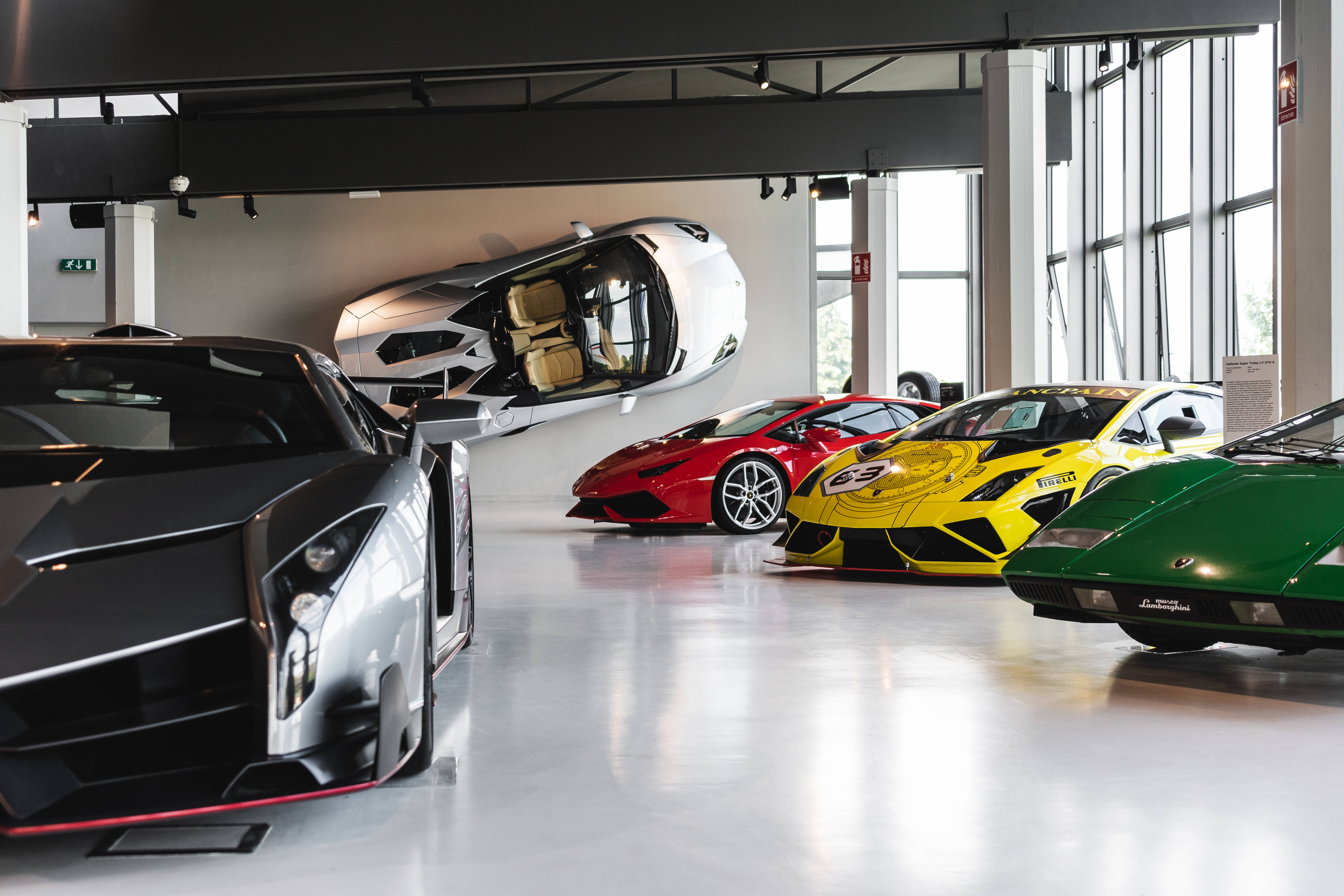Luxury 桌布 壁紙 — 一個時尚的現代車庫展示了一系列充滿活力的藍寶堅尼超級跑車，包括一個漂浮的銀色型號。