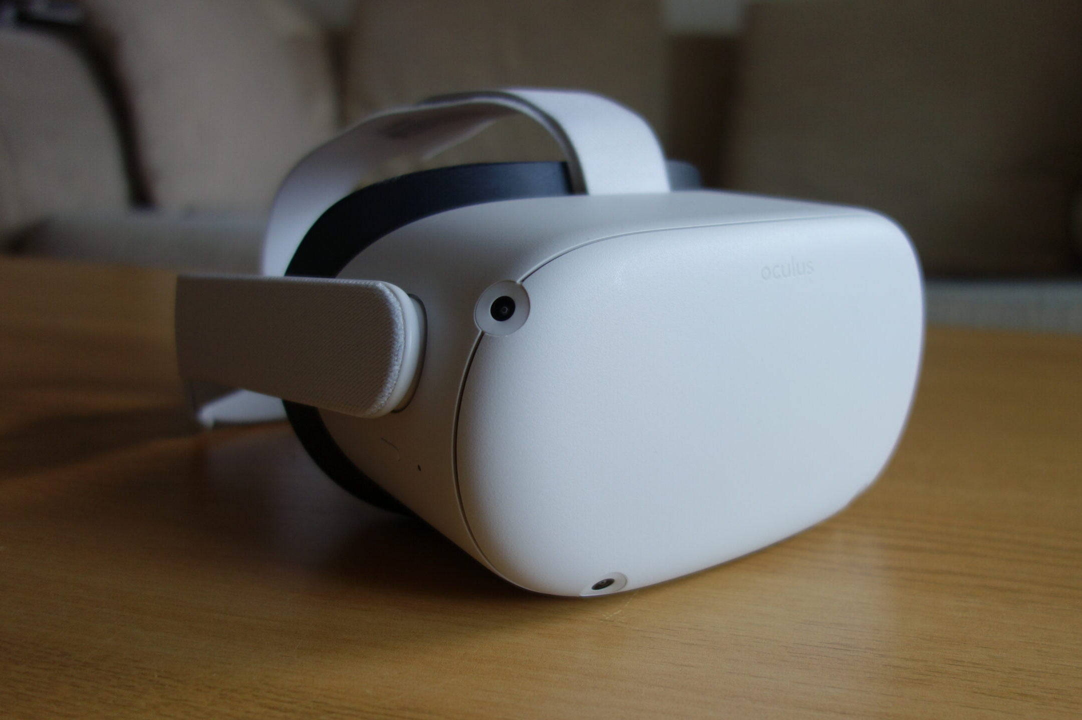 Quest 桌布 壁紙 — 一個時尚的白色Oculus VR頭戴式裝置放在木桌上，伴隨著柔和自然光線。