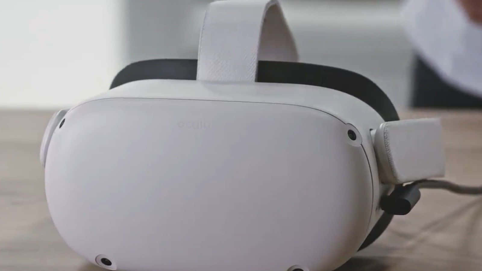 Oculus Quest 2 桌布 壁紙 — 一個時尚的白色Oculus VR頭戴式裝置放置在木質表面上，伴隨著柔和自然光線。