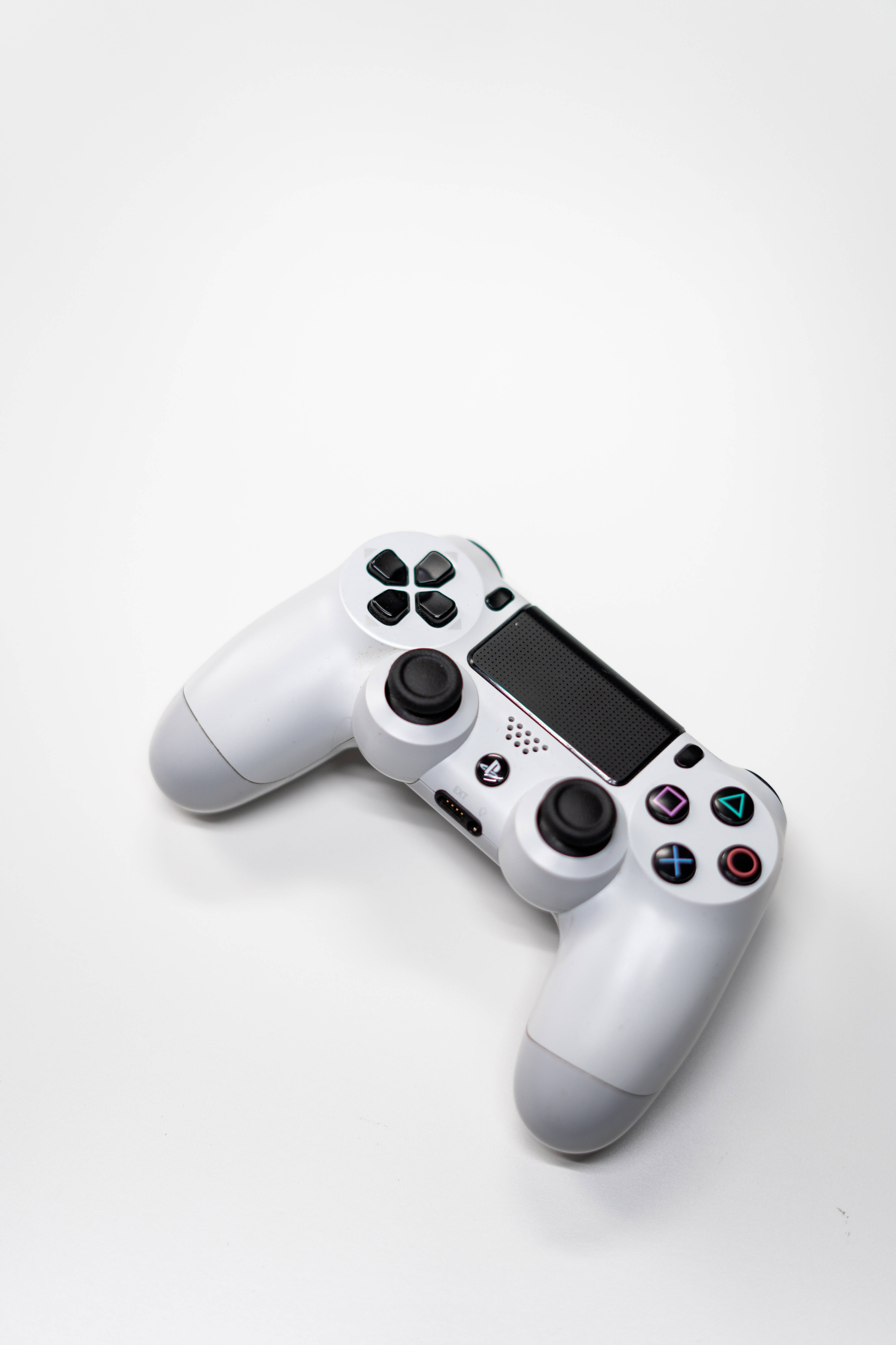 PlayStation 桌布 壁紙 — 一個時尚的白色PlayStation控制器放置在簡約的白色表面上，帶有柔和陰影。