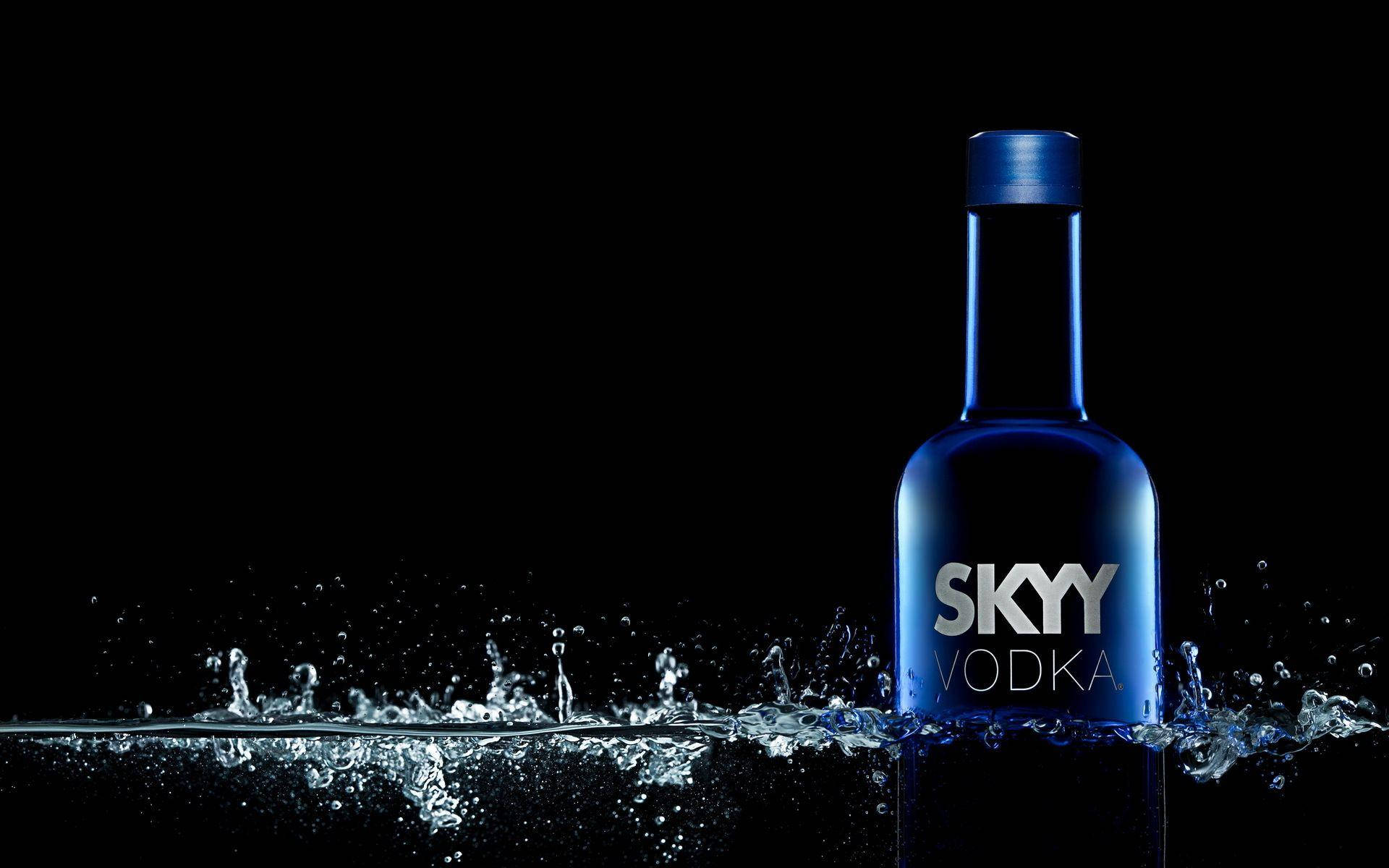 glass 桌布 壁紙 — 一個時尚的藍色Skyy Vodka酒瓶從動態的水花中浮現，背景為純黑色。