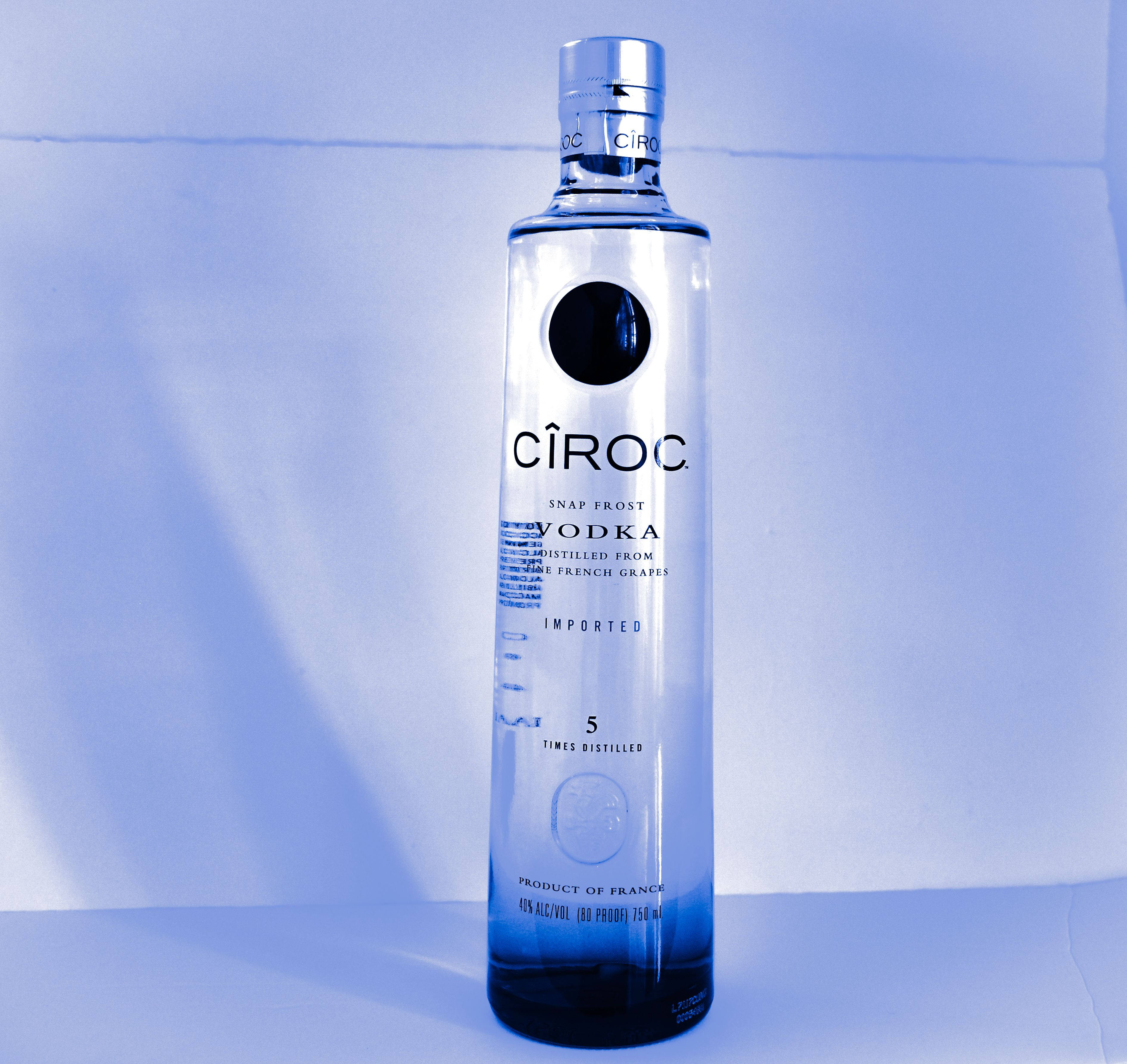 Drink 桌布 壁紙 — 一個時尚的藍色調Cîroc伏特加酒瓶，在柔和的藍色漸變背景上居中放置，帶有微妙的陰影。