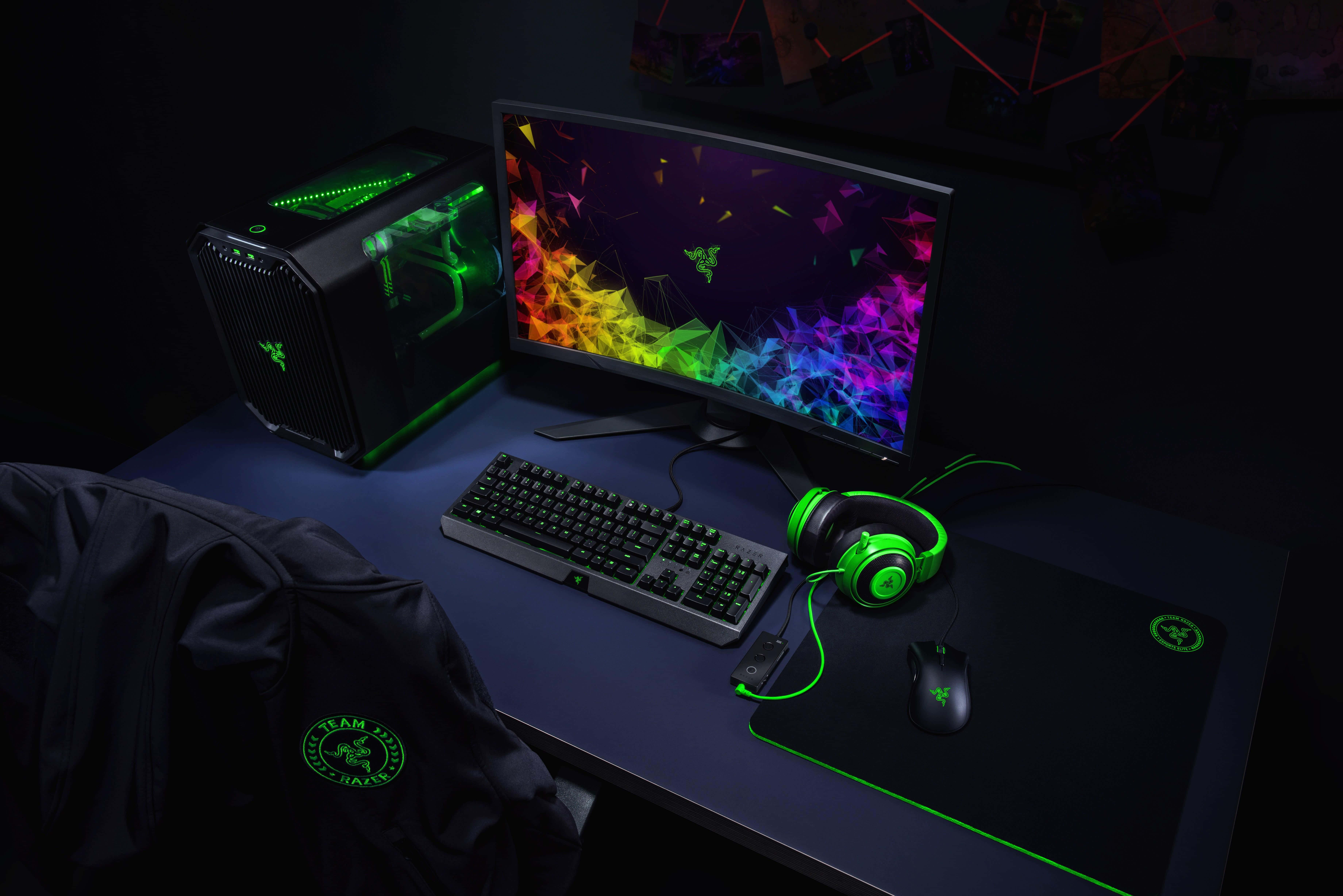 Gaming Setup 桌布 壁紙 — 一個時尚的遊戲設置，在黑暗的房間中，帶有發光的綠色Razer周邊設備和彎曲顯示器上充滿活力的彩虹壁紙。