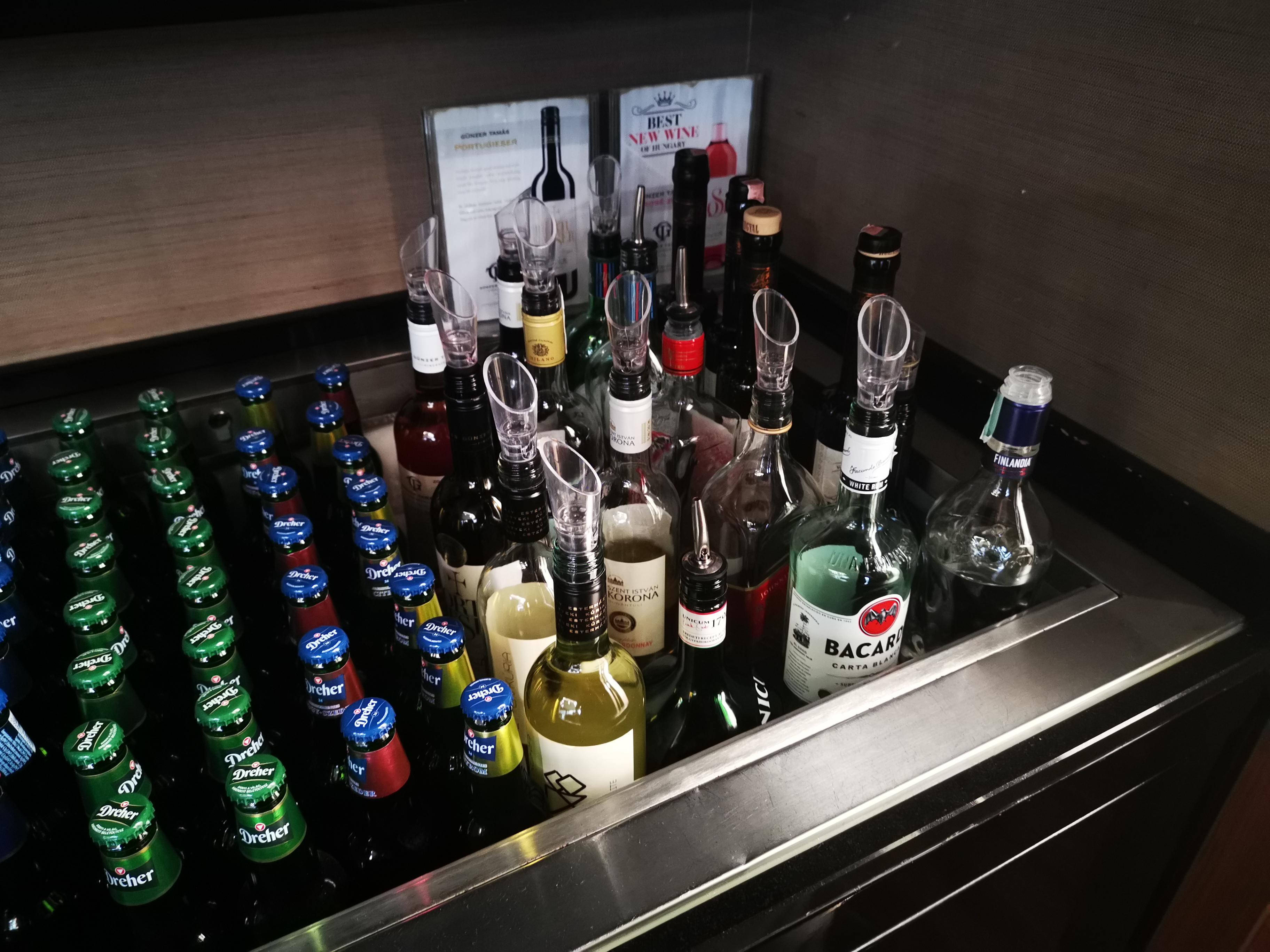 alcohol 桌布 壁紙 — 一個時尚的酒吧冰箱，內有排列整齊的啤酒瓶和各種帶有倒酒嘴的酒瓶。