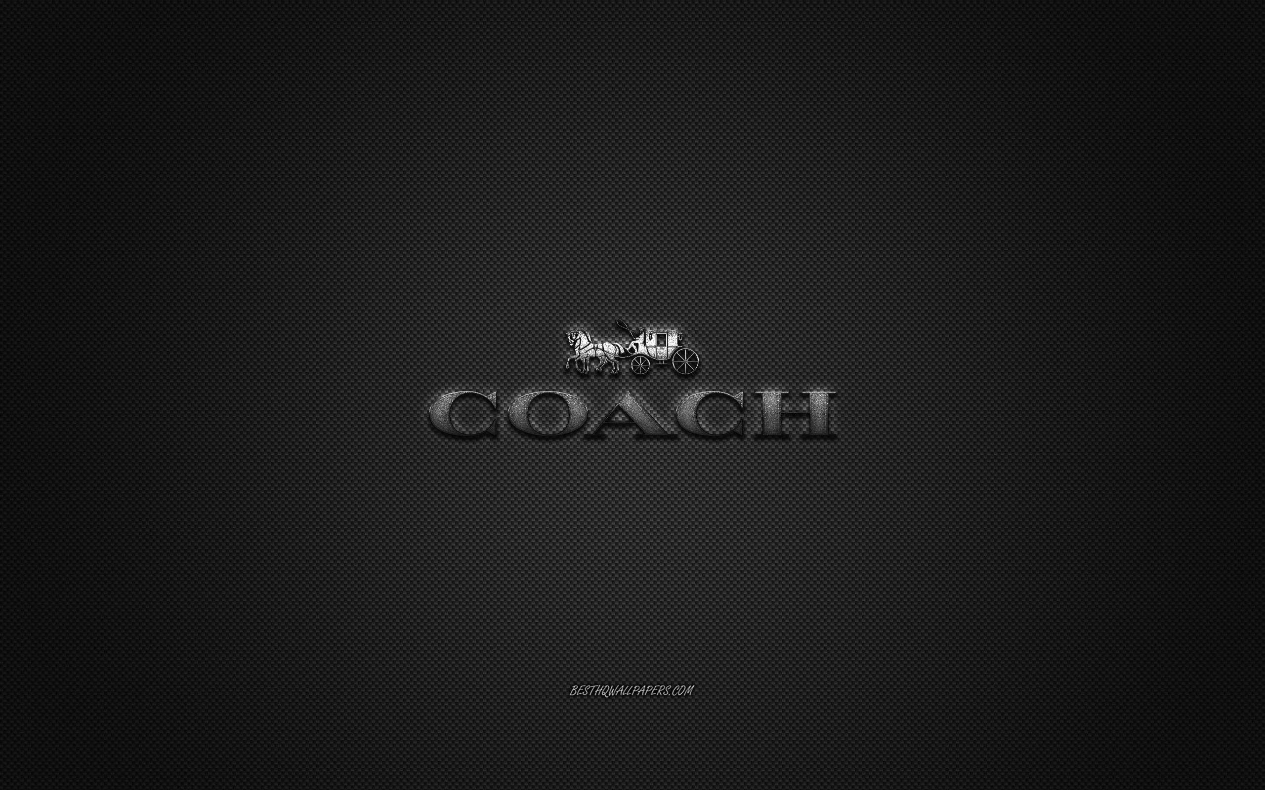 Coach 桌布 壁紙 — 一個時尚的金屬Coach標誌，中央有馬車圖案，置於深色紋理背景上。