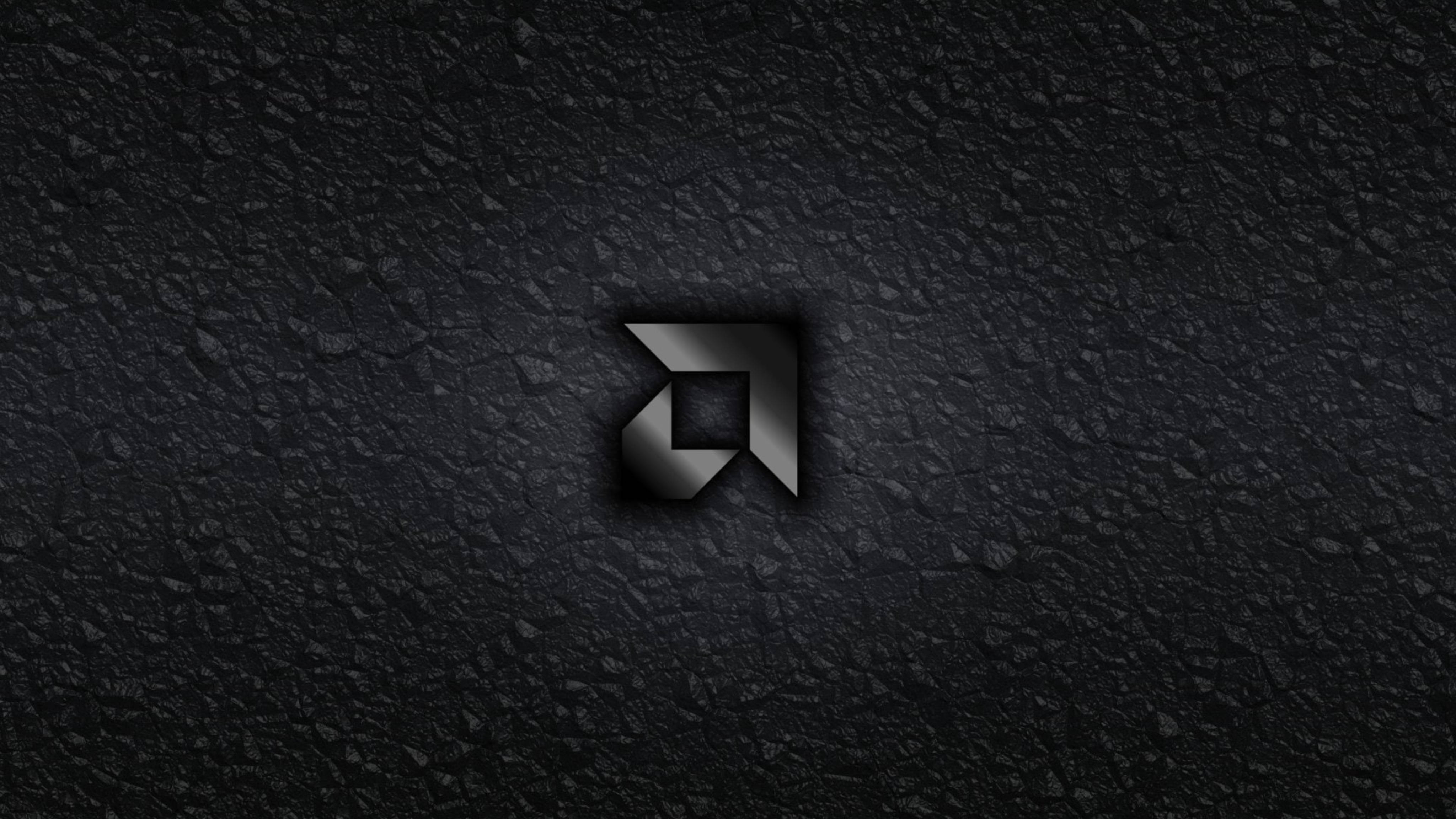 AMD 桌布 壁紙 — 一個時尚的金屬標誌，帶有銳利的幾何邊緣，居中放置在粗糙的深色紋理表面上。