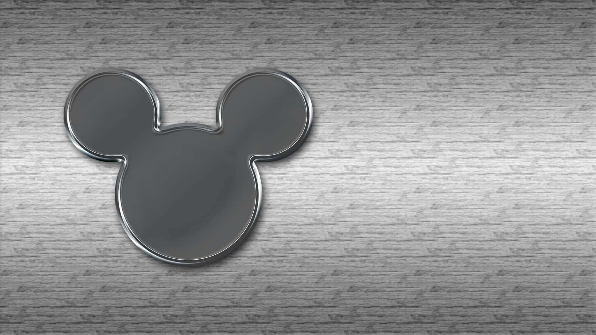 Mickey Mouse Desktop 桌布 壁紙 — 一個時尚的金屬米奇老鼠頭像徽章，放置在帶有細微紋理的拉絲鋼表面上。