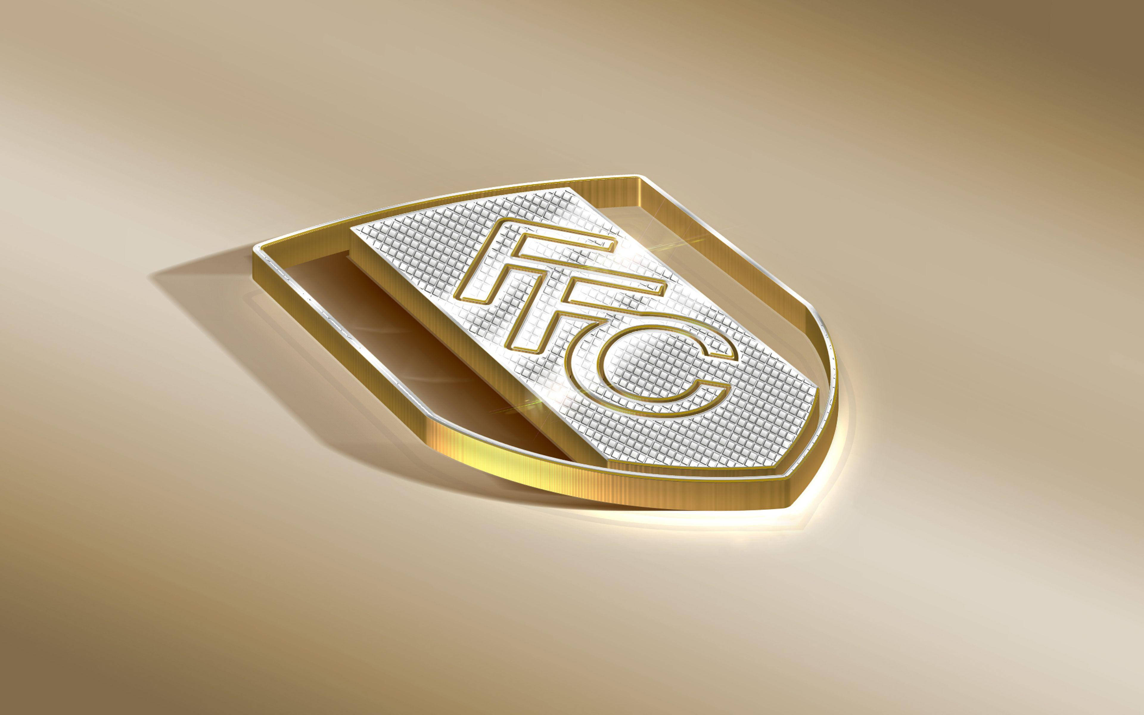 金色動態 桌布 壁紙 — 一個時尚的金銀盾牌標誌，上面有「FTC」字母，放在柔和的漸變米色表面上，在溫暖的燈光下。