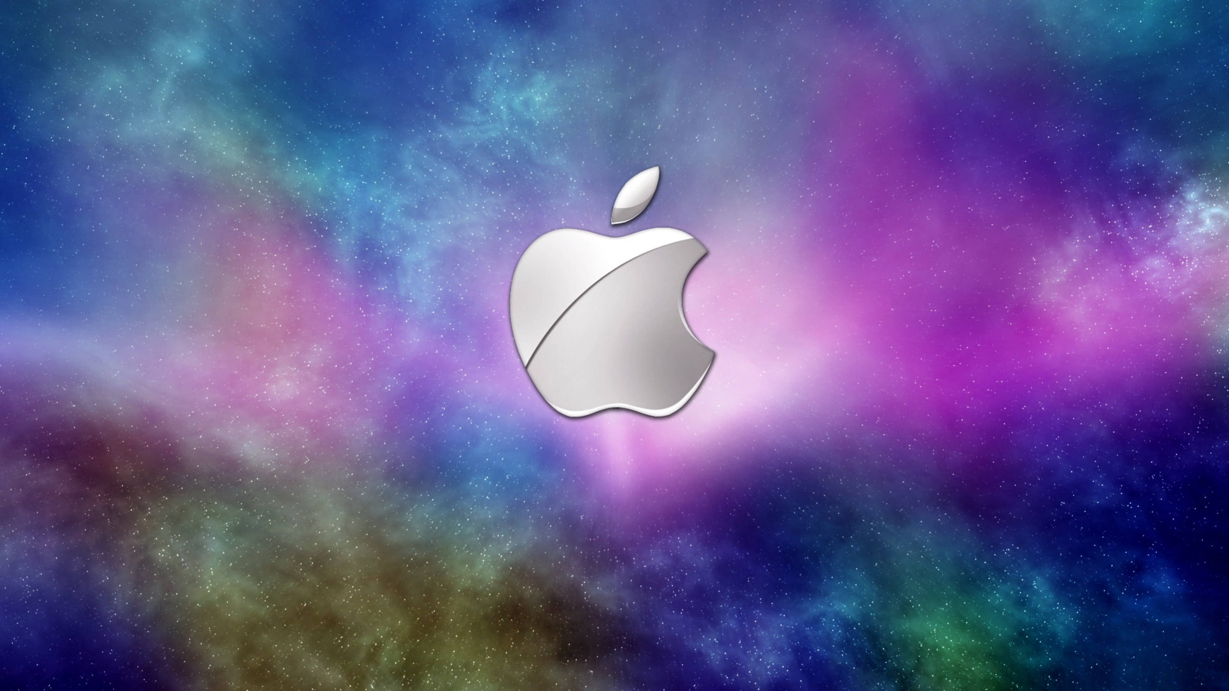 Apple 4K Ultra HD 桌布 壁紙 — 一個時尚的銀色 Apple 標誌漂浮在充滿活力的紫色、藍色和藍綠色宇宙星雲中，伴有閃爍的星星。