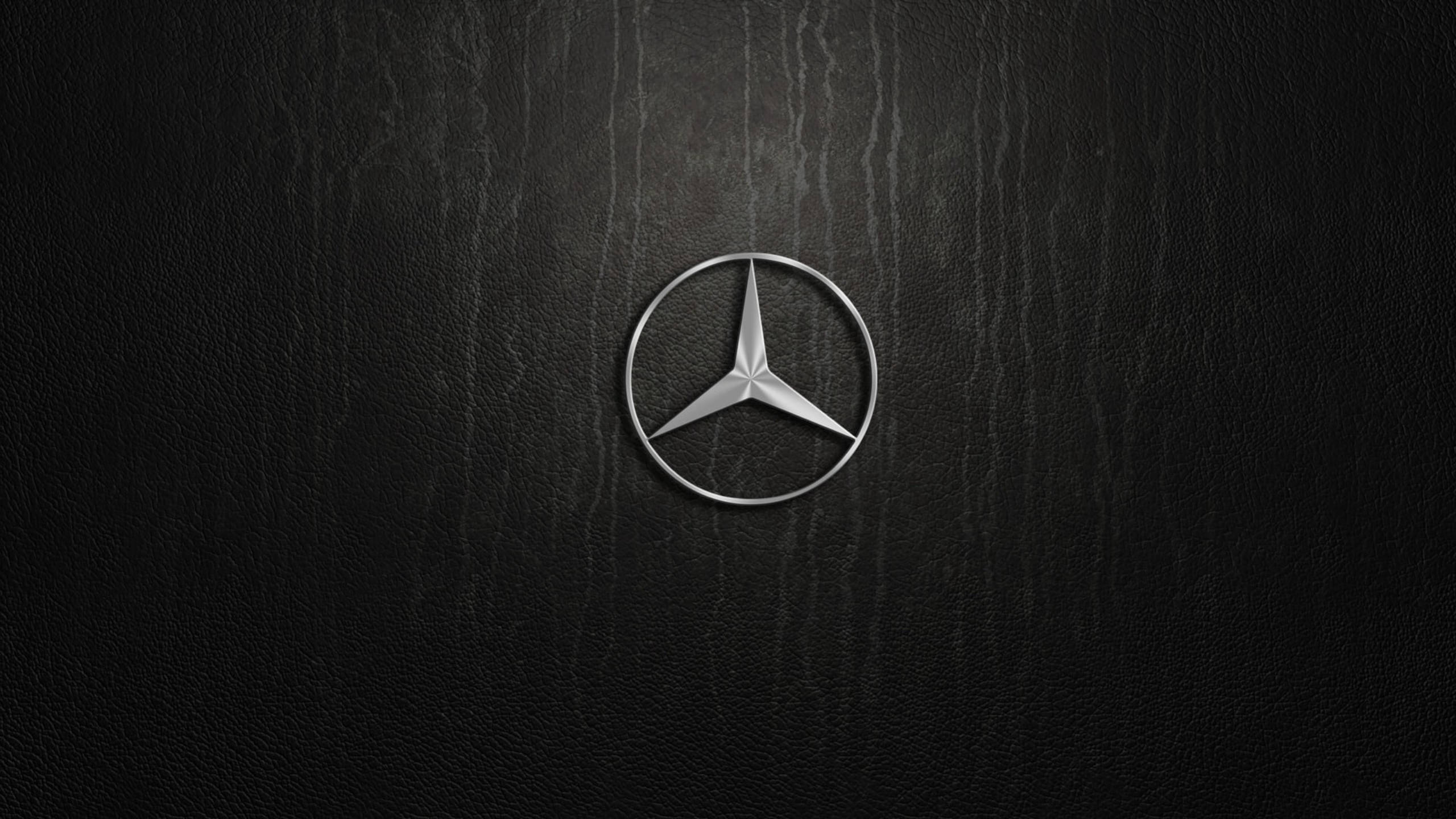 Silver 桌布 壁紙 — 一個時尚的銀色 Mercedes-Benz 標誌，置於帶有細微燈光高光的紋理黑色皮革表面中央。