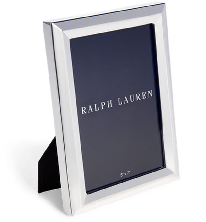 ralph lauren 桌布 壁紙 — 一個時尚的銀色 Ralph Lauren 相框，帶有深藍色內嵌，直立於一個有紋理的灰色支架上，背景為黑色。