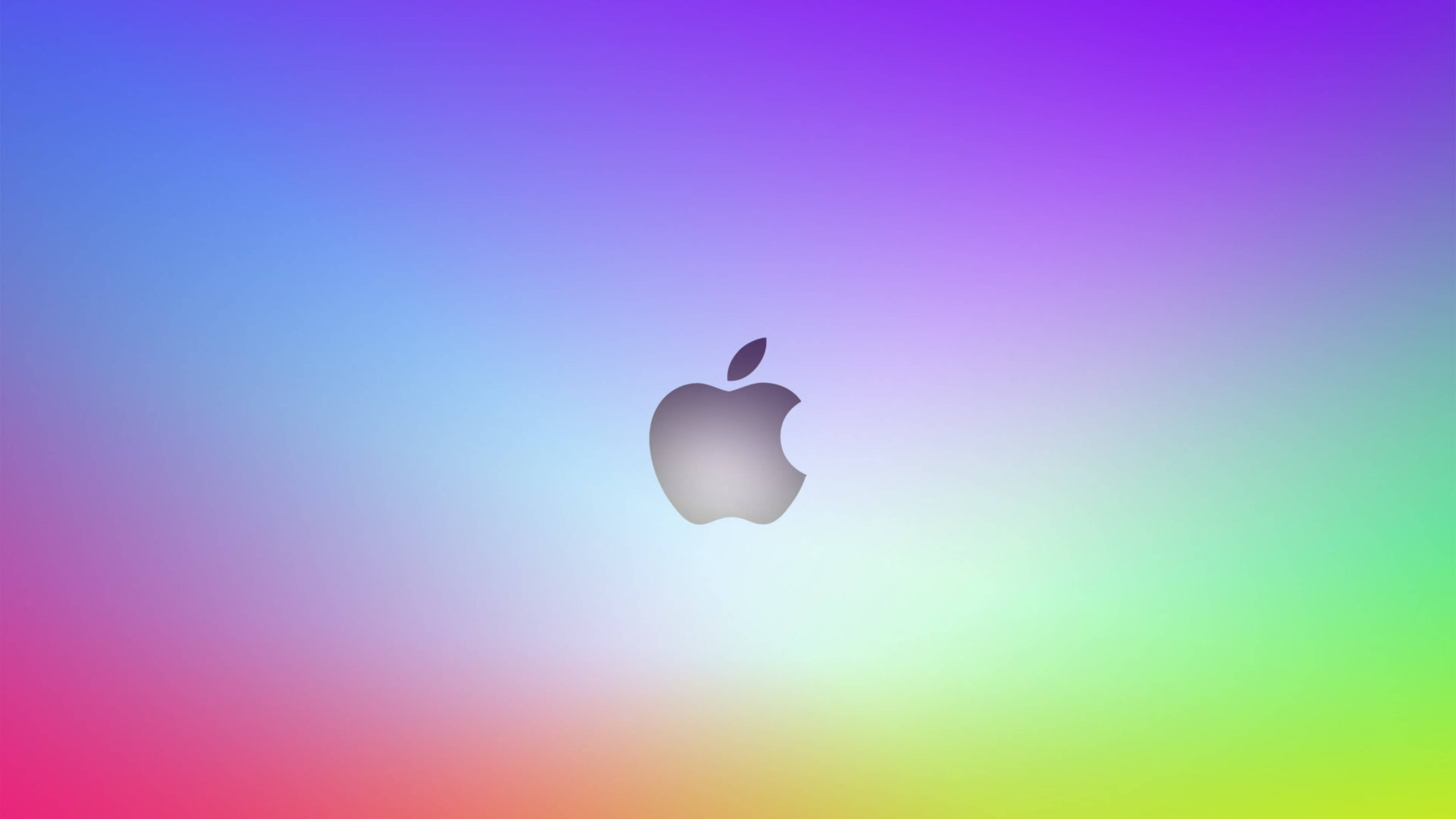 Apple 4K Ultra HD 桌布 壁紙 — 一個時尚的銀色Apple標誌，居中在鮮豔的彩虹漸變背景上。