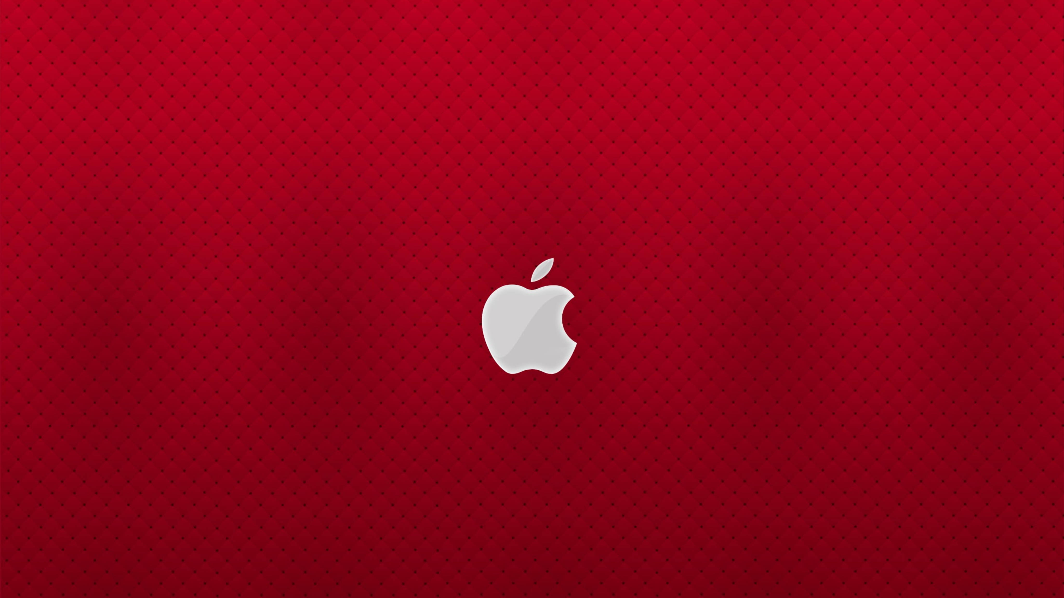 Apple 4K Ultra HD 桌布 壁紙 — 一個時尚的銀色Apple標誌，居中放置在帶有細微圓點圖案漸變的濃郁紅色背景上。