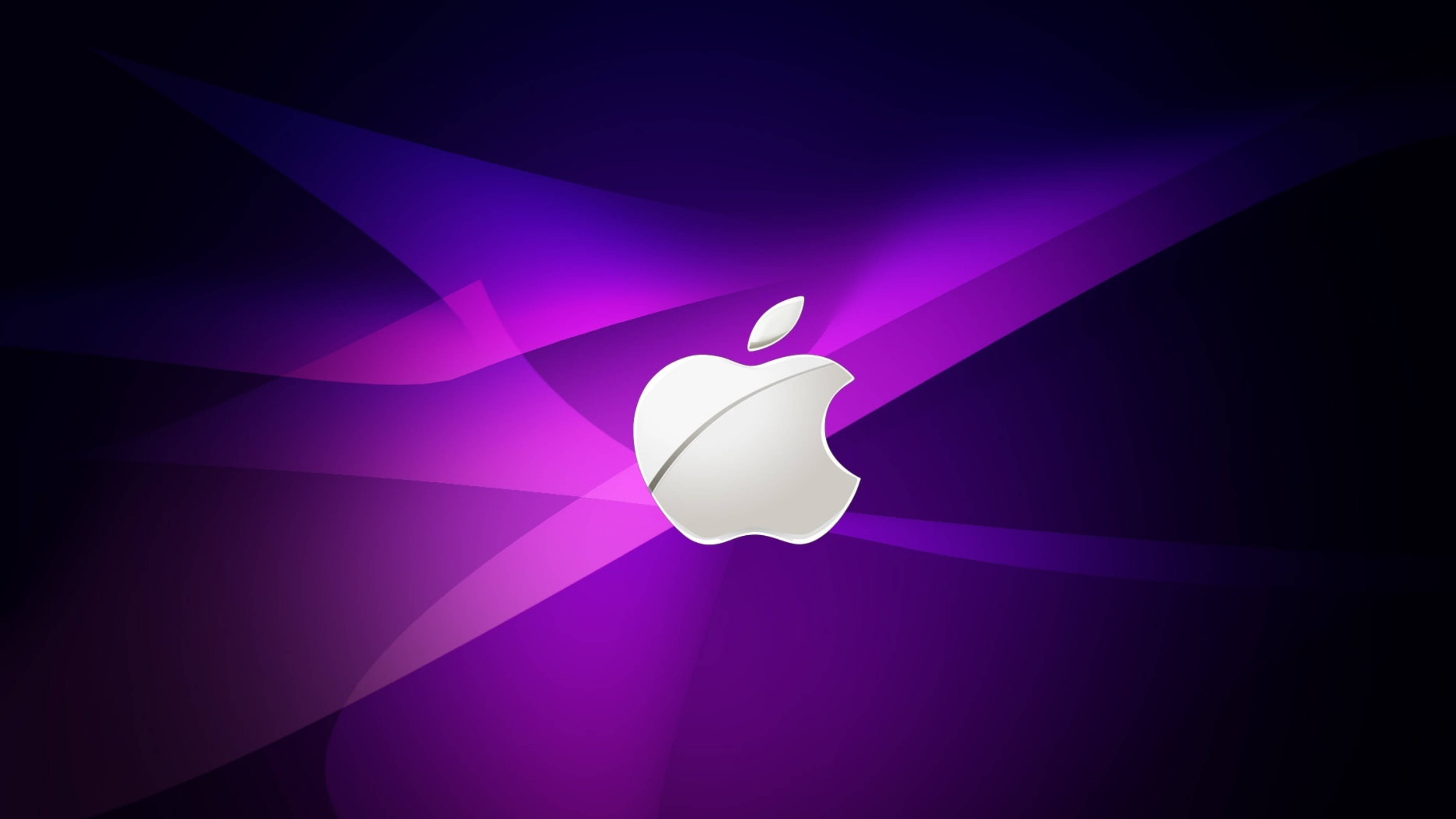 Apple 4K Ultra HD 桌布 壁紙 — 一個時尚的銀色Apple標誌在充滿動感光線的紫色和黑色抽象背景上發光。