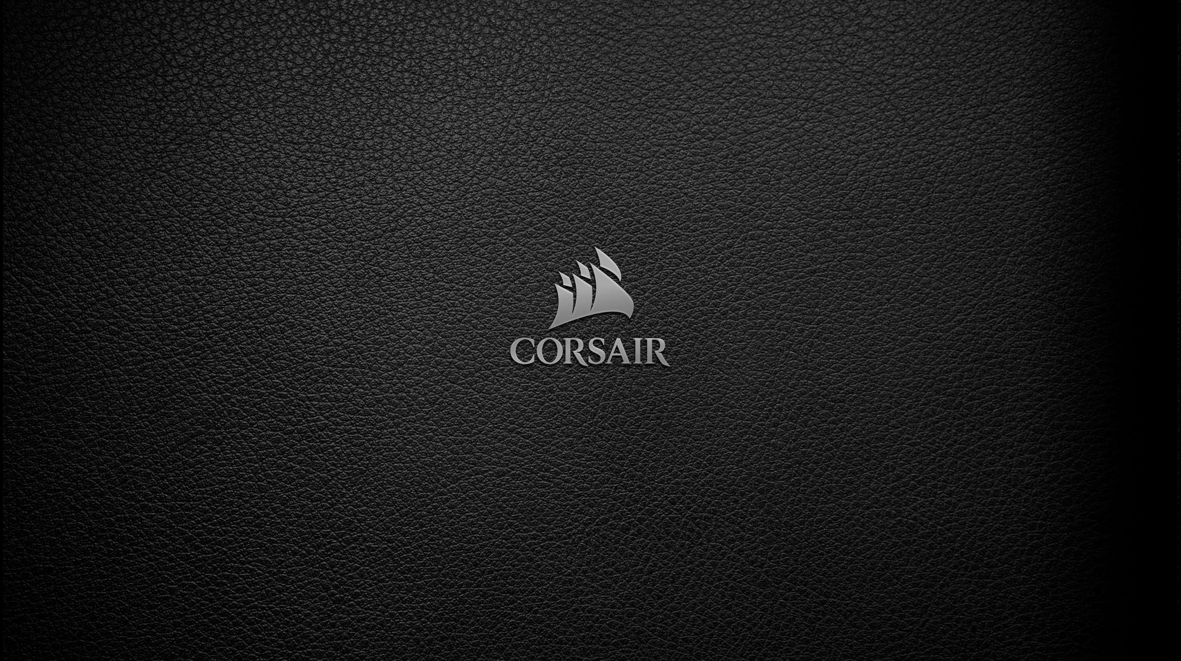 海盜船 桌布 壁紙 — 一個時尚的銀色Corsair標誌，置於帶有細微漸變照明的紋理黑色皮革背景中央。