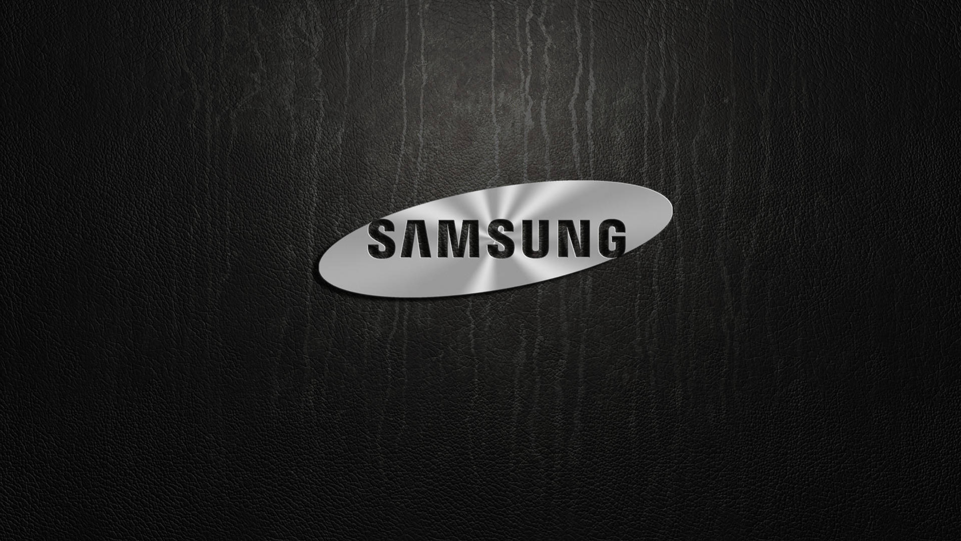 三星 桌布 壁紙 — 一個時尚的銀色Samsung標誌居中放置在帶有細微燈光高光的紋理黑色皮革表面上。