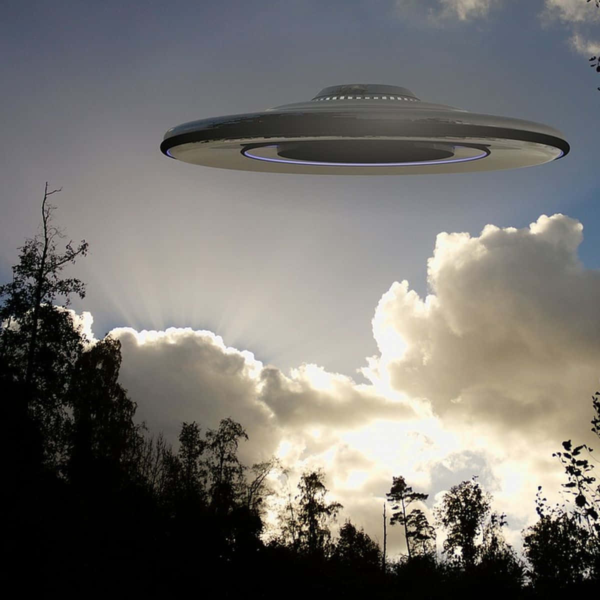 Real Ufo 桌布 壁紙 — 一個時尚的銀色UFO懸浮在森林剪影上方，背景是戲劇性的陽光天空和蓬鬆的雲朵。