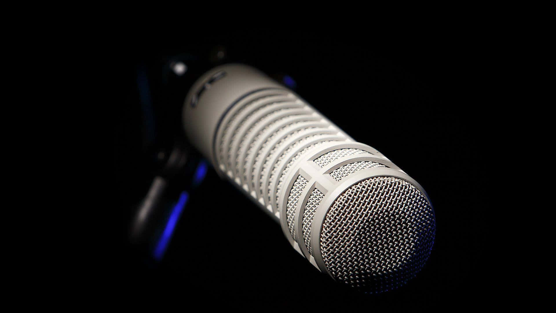 Voice 桌布 壁紙 — 一個時尚的銀色電容麥克風，帶有網格罩，在深黑色背景下柔和發光。