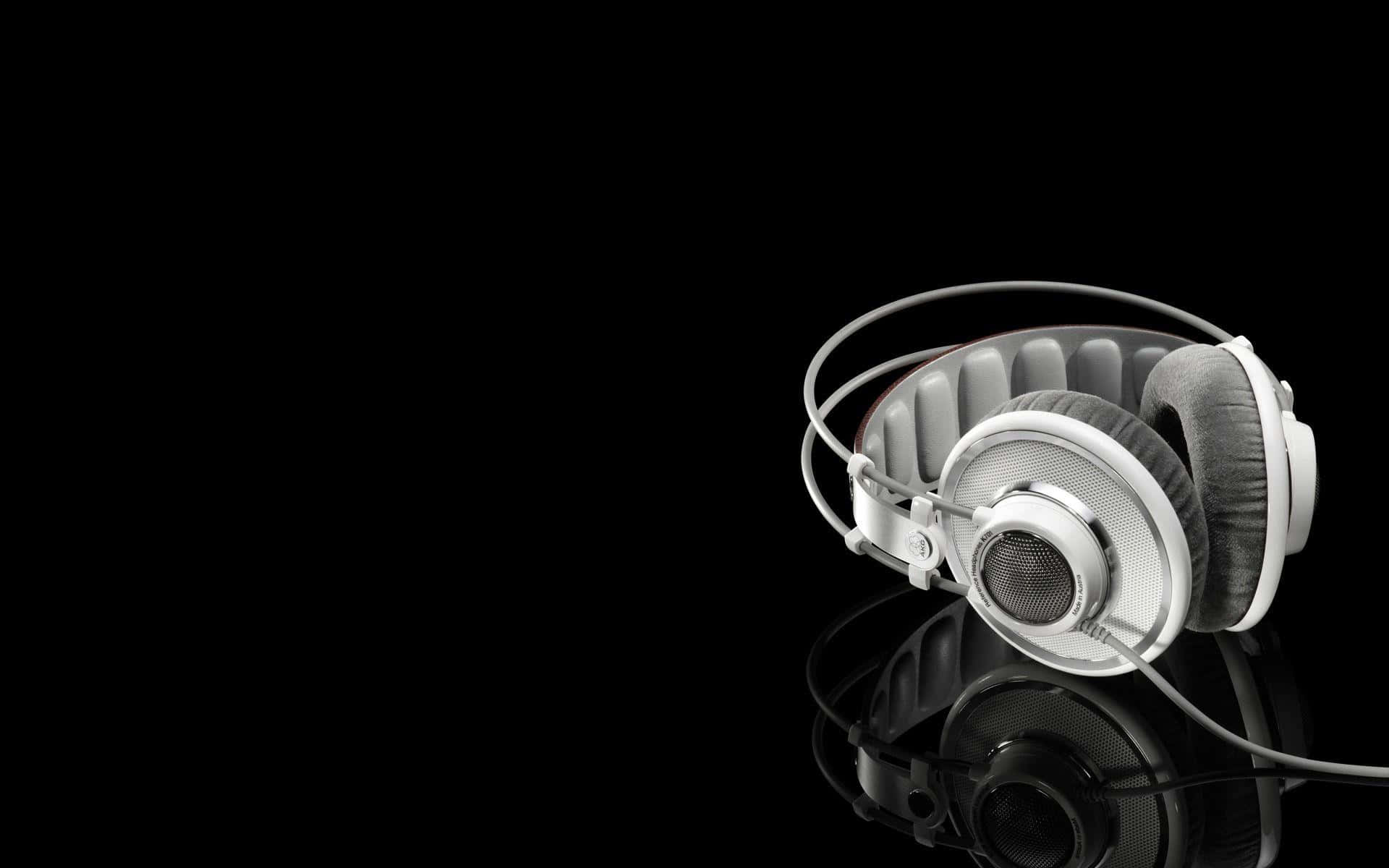 Headphones 桌布 壁紙 — 一個時尚的銀色頭戴式耳機放在反射黑色表面上，搭配極簡工作室燈光。