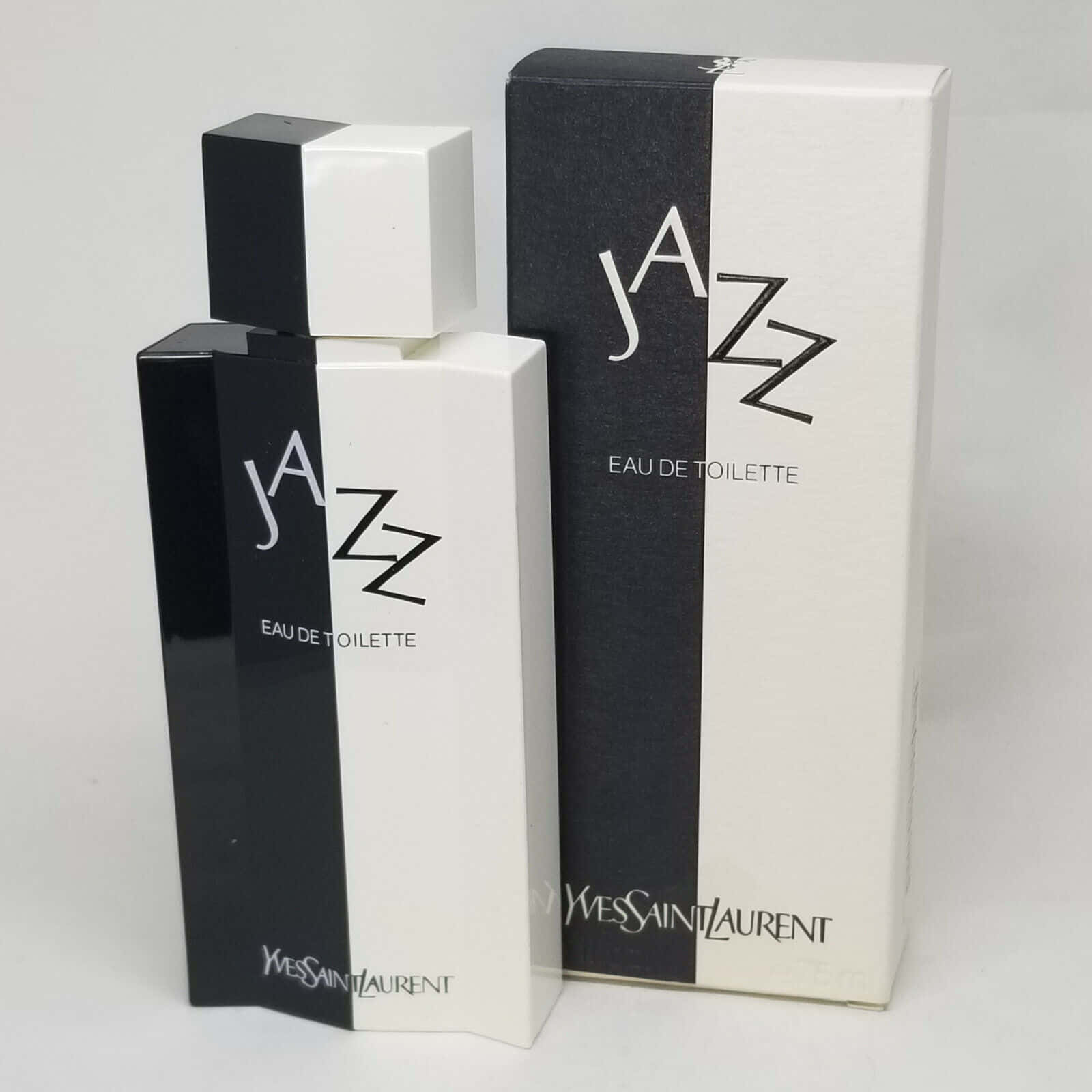 Ysl 桌布 壁紙 — 一個時尚的黑白 Yves Saint Laurent Jazz Eau de Toilette 香水瓶，旁邊是其配套的盒子，背景為純白色。