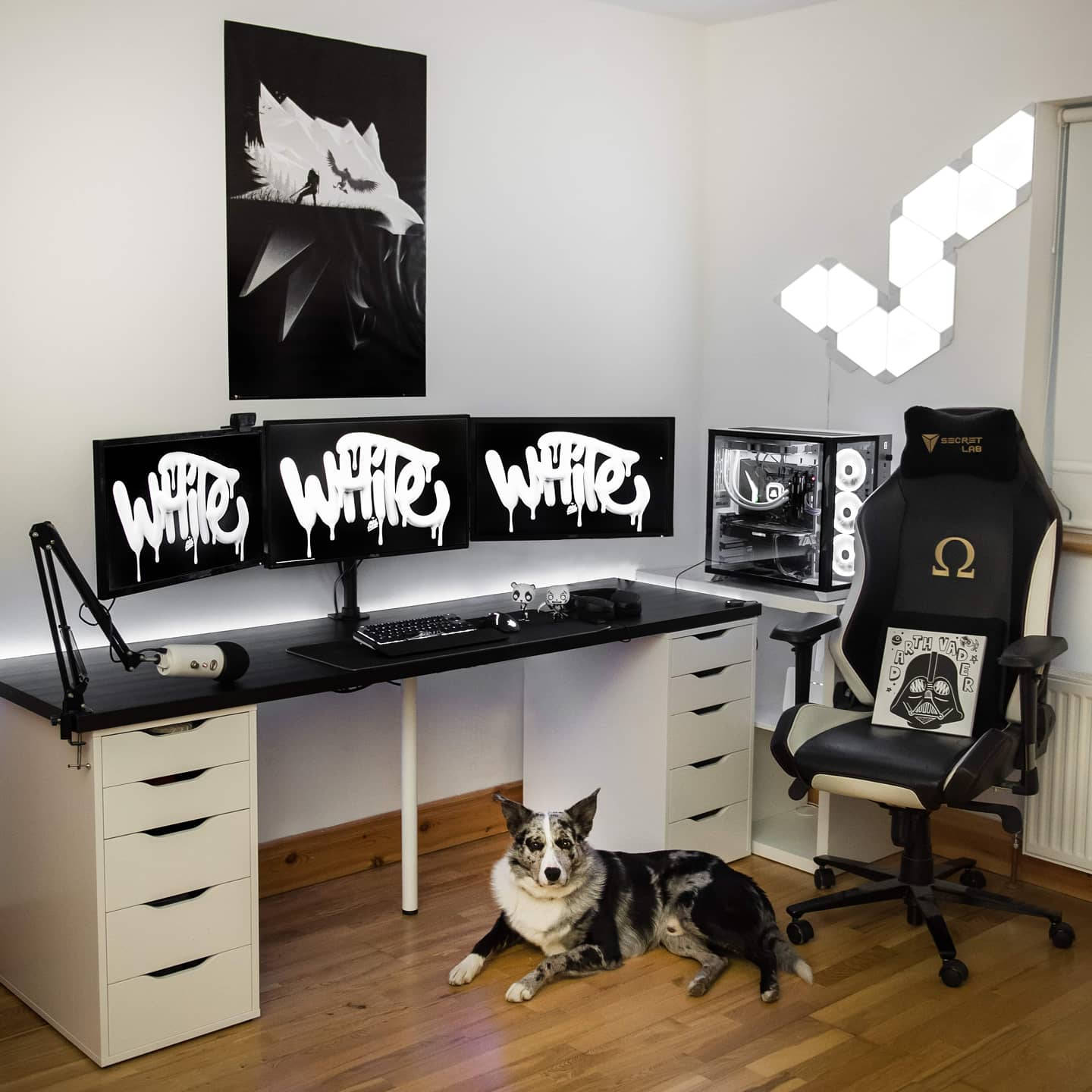 White Pc 桌布 壁紙 — 一個時尚的黑白遊戲設置，三個顯示器以塗鴉風格顯示「WHITE」，一隻狗在木地板上休息，高背椅上有一個黑武士枕頭。