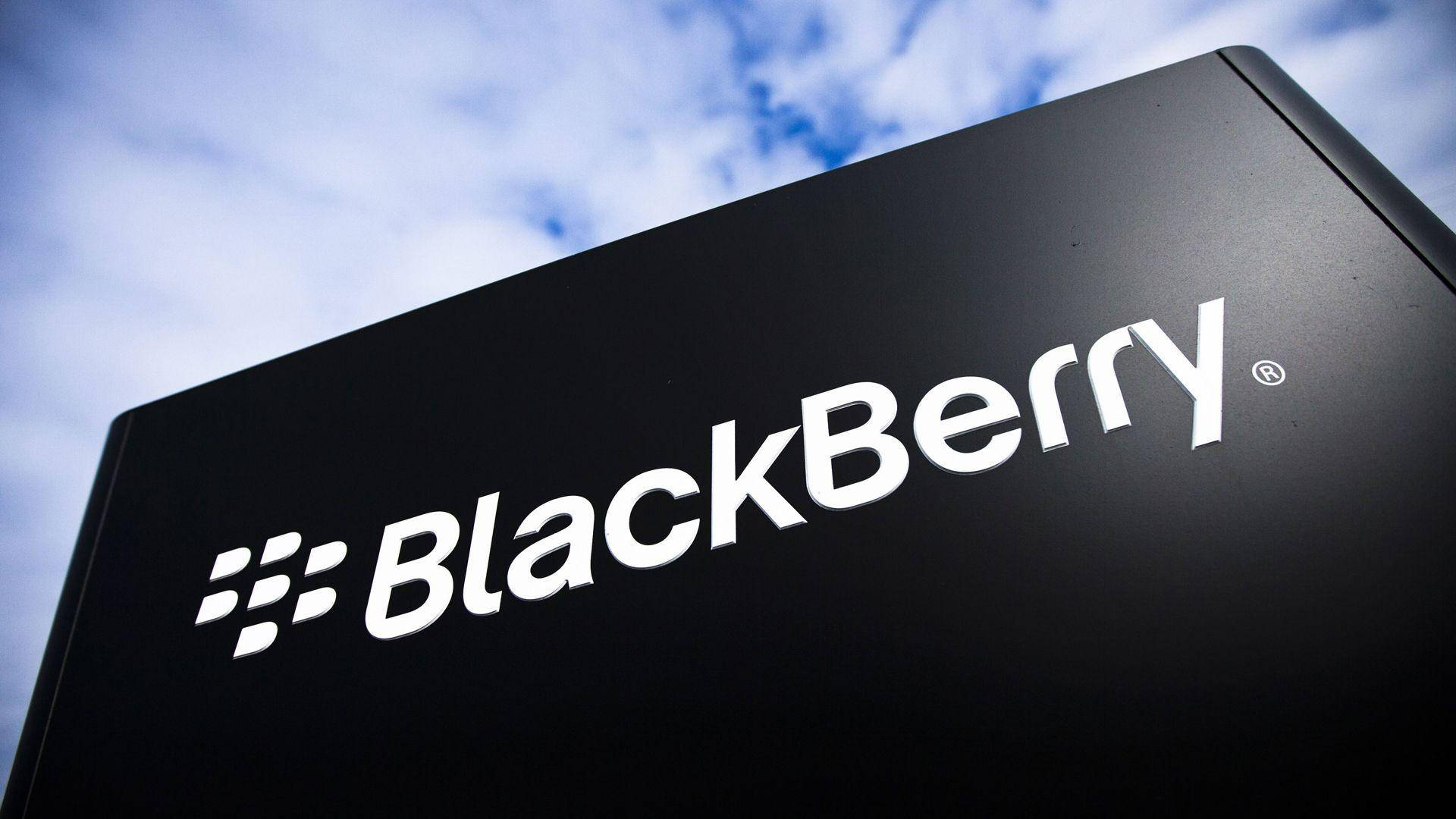 Blackberry 桌布 壁紙 — 一個時尚的黑色BlackBerry標誌牌，帶有白色標誌，矗立在晴朗的藍天和白雲之間。