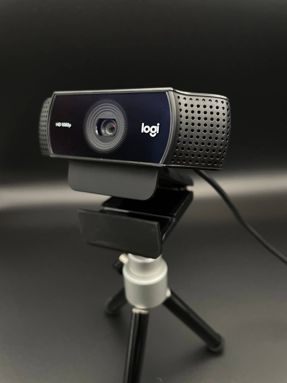 Webcam 桌布 壁紙 — 一個時尚的黑色Logitech HD網路攝影機安裝在一個小三腳架上，背景為深色漸變。