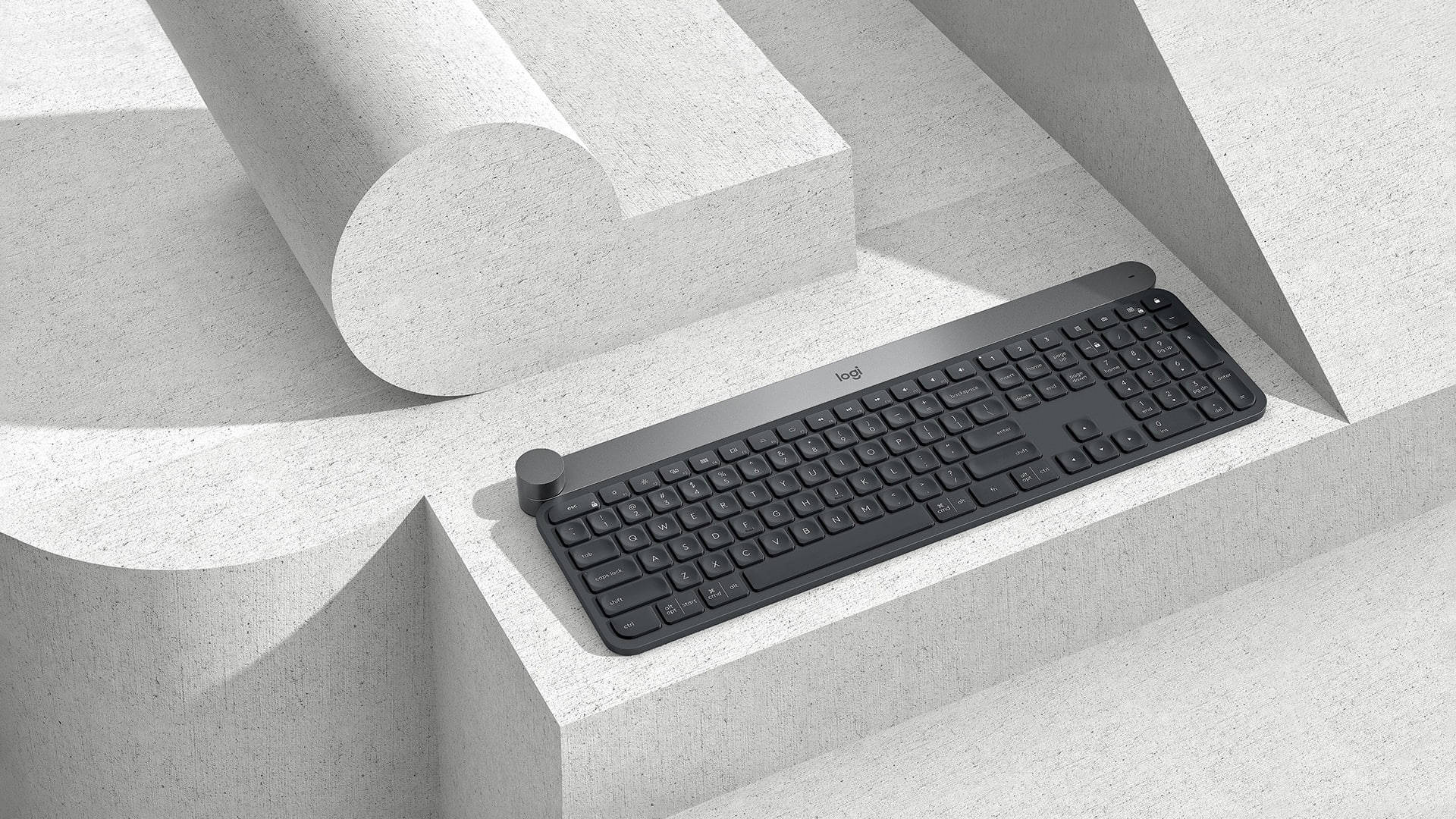 羅技 桌布 壁紙 — 一個時尚的黑色Logitech鍵盤在明亮的日光下，放置在簡約紋理混凝土階梯上。