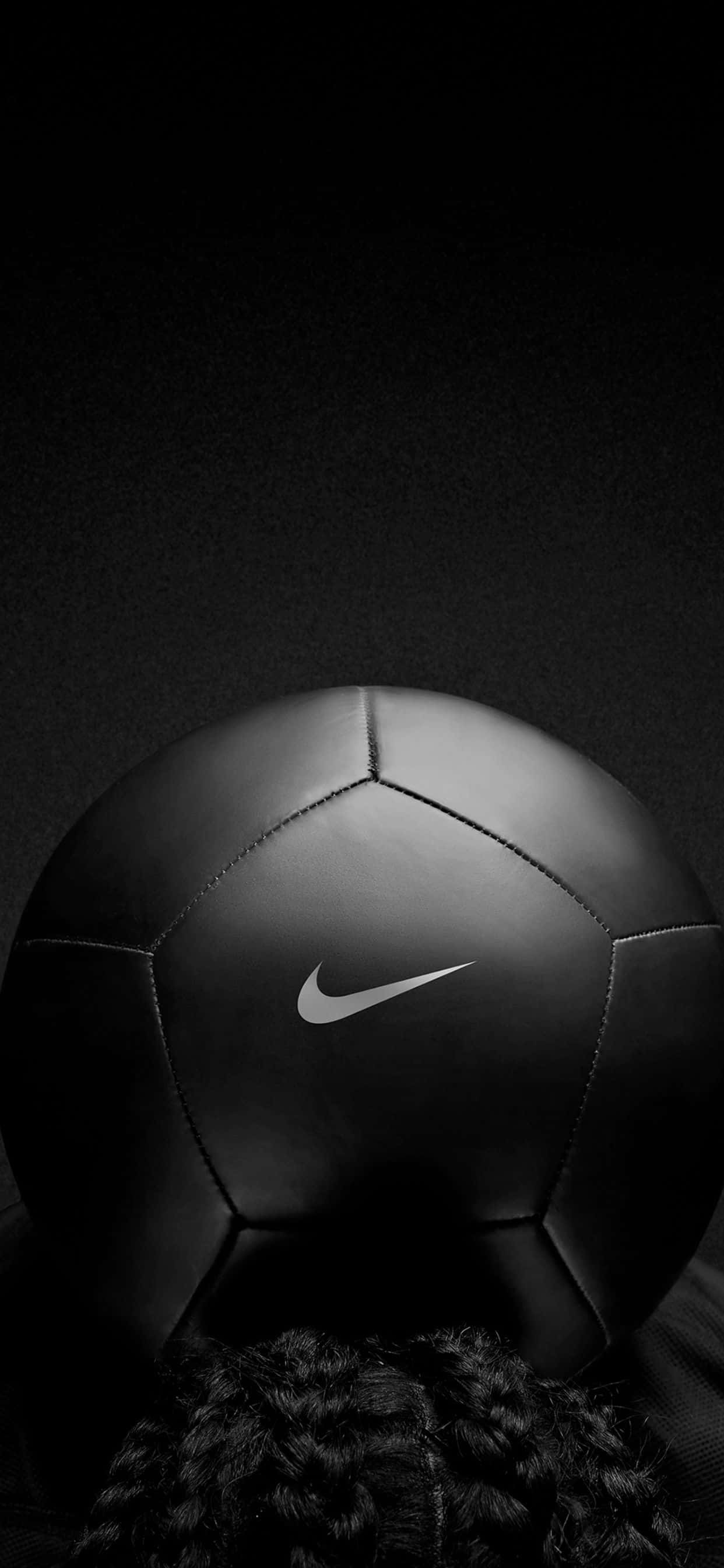 Soccer Aesthetic 桌布 壁紙 — 一個時尚的黑色Nike足球，帶有銀色swoosh標誌，靠在深色紋理背景上，部分由辮子頭髮框住。