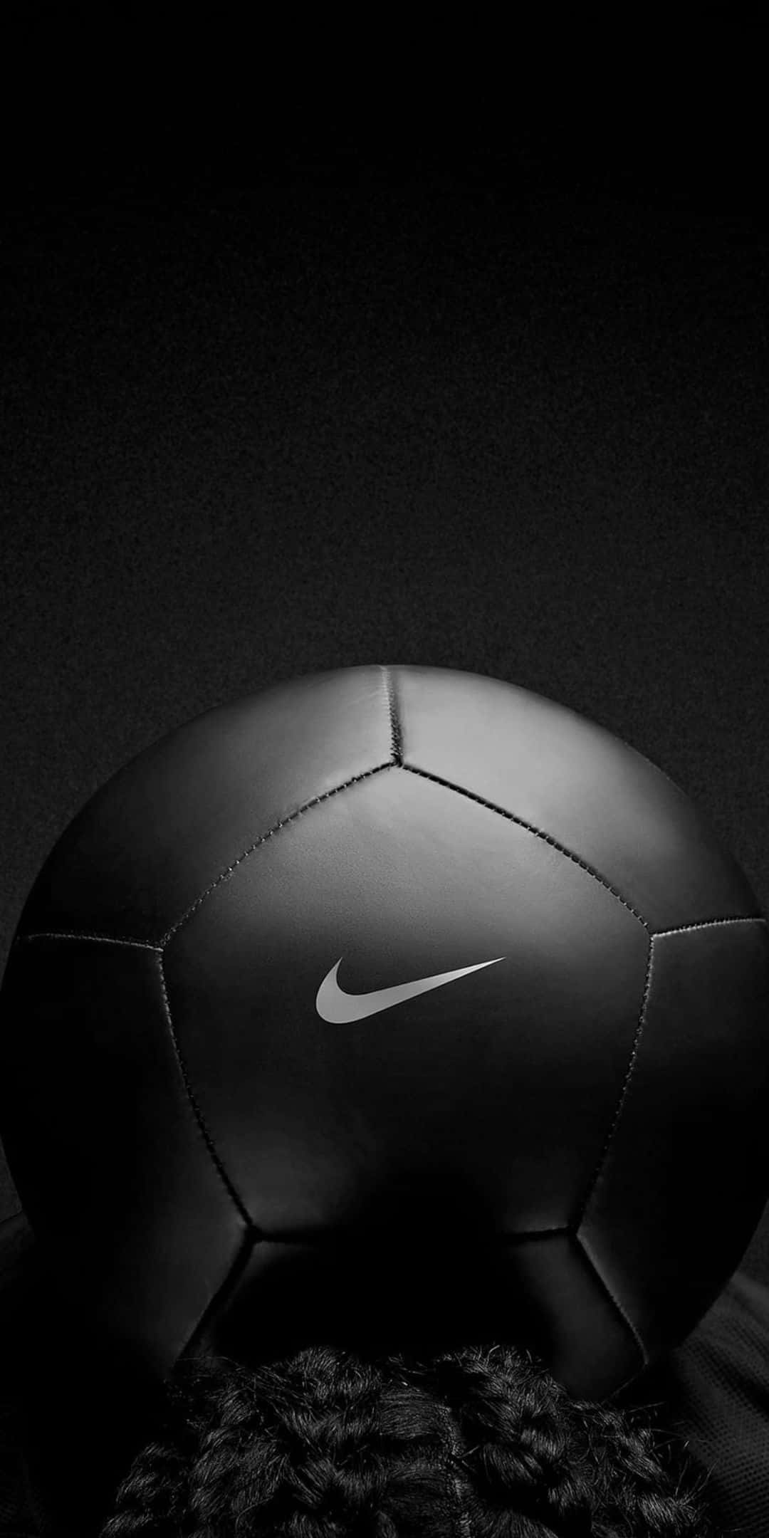 ball 桌布 壁紙 — 一個時尚的黑色Nike足球，帶有白色標誌，放置在深色紋理背景上，底部有捲髮作為框架。