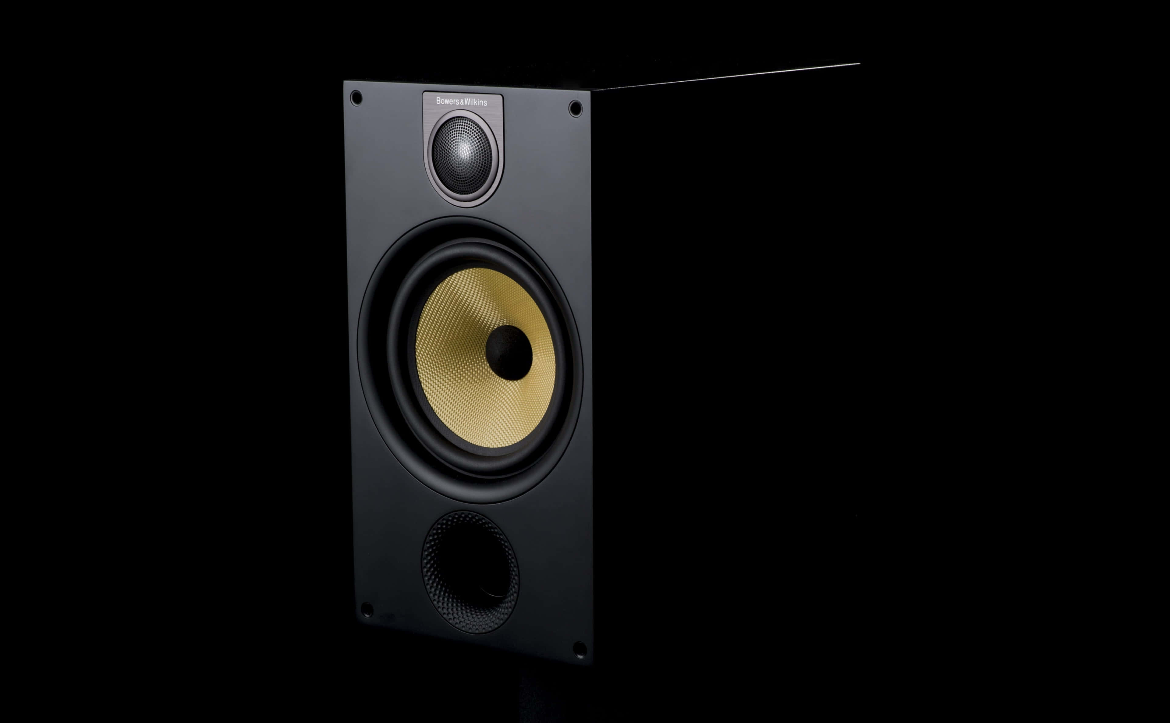 Speaker 桌布 壁紙 — 一個時尚的黑色揚聲器，帶有金色錐體，在純黑色背景下，在攝影棚燈光下孤立地站立。